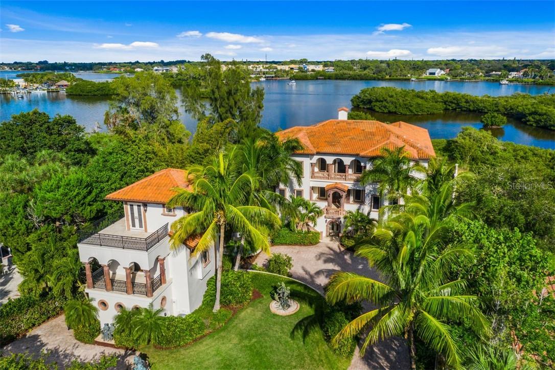 Stunning Bayfront gated masterpiece built in 2006 and located on Casey Key in Sarasota one of the most exclusive barrier islands on the west coast of Florida. Modeled after an 18th Century Tuscan mansion all of the finishes were imported and many were hand carved, including the wooden doors, cabinetry, stone columns and even the stone sinks. The European style Interior Grand Courtyard greets you with a 26 foot illuminated beamed ceiling and a 12 foot hand carved stone fireplace plus expansive views of the Infinity Pool, dock, Little Sarasota Bay and the Intracoastal Waterway beyond. The spectacular kitchen and family room are very inviting with gorgeous hand carved wooden cabinetry, a gas stove, large walk-in pantry, multiple dishwashers, three sinks and the same expansive bay views. The elegant Outdoor Pool-Side Family Room with a hand carved stone fireplace and framed in beautiful hand carved stone columns might be your favorite room of the house to relax, especially on those chilly Florida nights! The main house is serviced by an elevator on all three levels, there are four bedrooms plus a handsome library/office, the flooring is stone and imported wide plank wood flooring throughout the residence. The Master Suite is fabulous with well-appointed his and hers private bathrooms, a beautiful closet, and a large bedroom opening to a sunset terrace. The west and east upper promenades both offer large terraces for relaxing or just enjoying the Gulf breezes. The outdoor living area is sensational with the infinity edge pool, outdoor fireplace and expansive outdoor living space, plus the dock! The dock features a 10K boat lift plus there are two jet-ski docks located on each side of the wooden dock. An exquisite guest house accompanies this mansion and is connected by a majestic confederate jasmine covered trellis. Halfway along the trellis pathway you'll encounter a lovely tiered fountain which pools below at the motor court. The towering guest house offers endless useful possibilities such as an excellent artist studio or a wonderful home office. The first level is a living room, kitchen and half bath as well as laundry, the second level is the bedroom and full bathroom with the third level being a loft to the sunset deck; and from that third level deck you see the sun touch the water at sunset. There are terraces and patios on every level of the guesthouse to enjoy the great Florida lifestyle! The main house has a bonus underneath in that there is a five car garage plus a large storage area; and remember the elevator service all three levels of the residence starting at the garage. This property also comes with a private deeded easement to the Gulf of Mexico.