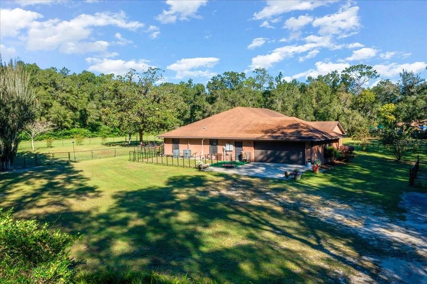 A rare Ocala gem — custom log-cabin inspired home for rent on 3 acres in North Pine Ranchettes. This 3-bedroom, 2-bath residence built in 2014 offers over 2,300 sq ft of living space featuring real wood interior walls and ceilings, custom cabinetry, wood flooring, and vaulted ceilings.
The open-concept kitchen includes an extended island with granite countertops, premium wood finishes, and custom lighting. Large picture windows overlook the surrounding 3 acres of A-1 zoned land with multiple fenced areas suitable for horses, pets, or gardening.
A detached guest house provides additional living space ideal for extended family or office use. An additional fenced area with its own septic system is available for potential future use.
The long private driveway leads to a peaceful setting surrounded by mature oaks and pines. A spacious covered patio offers the perfect spot for outdoor enjoyment and gatherings.
Conveniently located just minutes from major retail, grocery stores, medical facilities, and other local amenities.