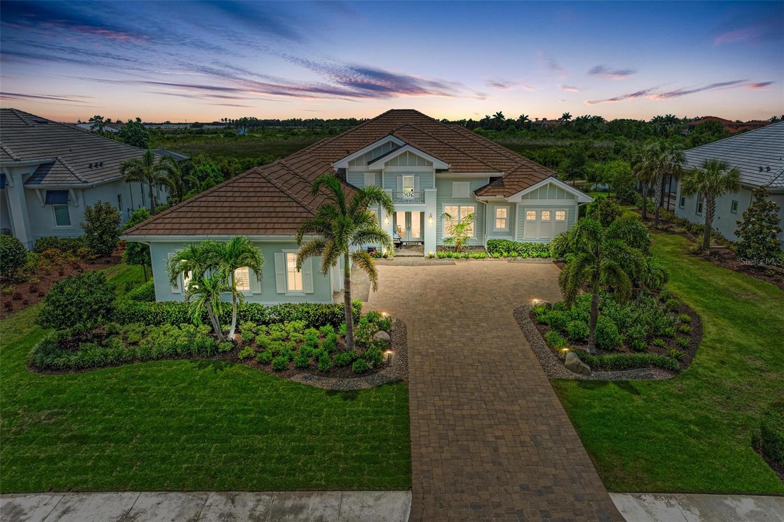 Embrace luxury living in this former model home built by Stock Signature Homes in the premier gated community of The Lake Club. Set on beautifully landscaped grounds and featuring soaring 12’ ceilings throughout, this home exudes an atmosphere of grandeur. The expansive great room, kitchen, and dining room area flow together harmoniously and seamlessly connect to the outdoor screened patio through large sliders, creating the perfect space for entertaining and everyday living. The gourmet kitchen is a chef’s delight with quartz countertops, a large island with seating for four, a gas stovetop, and stainless-steel appliances.
The spacious family room offers additional access to the patio, while an impressive study/office with double glass doors and a tray ceiling provides a sophisticated space for work or relaxation. The well-equipped laundry room includes plenty of countertop space, a sink, and ample cabinetry for storage.
Relax and rejuvenate in the oversized primary suite, which boasts a tray ceiling, abundant natural light, double glass doors leading to the patio, and two walk-in closets. The spa-like bath offers a large frameless glass walk-in shower and a soaking tub for ultimate relaxation. Two generous guest suites provide comfort and privacy, with one featuring a full bath.
Enjoy seamless indoor-outdoor living with disappearing pocket sliders that open from the great room to an outdoor oasis featuring a stunning pool and spa, covered seating areas, panoramic screen for unobstructed nature views of a lake, trees, wildlife, and preserves, built-in gas grill with hood, remote-controlled sun screen, and summer kitchen for alfresco dining. Additional highlights of the home include a Generac whole-house generator for peace of mind and a three-car garage with plenty of storage.
Residents of The Lake Club enjoy a wealth of amenities, including the expansive 20,000-square-foot Grand Clubhouse, featuring a state-of-the-art fitness center, banquet room, indoor/outdoor bar, restaurant, spa, yoga room, and billiards room. Residents can also stay active on the tennis, pickleball, and basketball courts or unwind by the resort-style pool. Parks and walking trails offer scenic escapes for nature lovers. The Lake Club's prime location offers easy access to everything Main Street at Lakewood Ranch, UTC, Nathan Benderson Park, Sarasota National Golf Course, downtown Sarasota, and world-famous beaches.