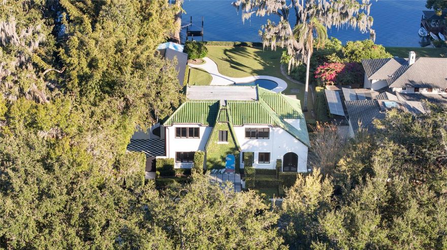 Steeped in history and masterfully reimagined, this 1926 Winter Park estate blends architectural provenance with modern refinement. Thoughtfully restored by E2 Homes, the residence honors its past while offering contemporary sophistication. Unlike many historic properties, it is free from preservation restrictions, allowing for seamless enhancements. On the shores of Lake Virginia along the desirable Winter Park Chain of Lakes, this 3,181-square-foot estate features four bedrooms, three full baths and two half baths, with three bedrooms in main house plus detached one-bedroom guest cottage. The second-floor primary suite is a private retreat with a Juliet balcony, dual closets and an elegantly appointed bath with an expansive dual-sink vanity, a separate water closet, and a washroom with a shower-tub combination. A Jack and Jill bath, adorned with Maharam wallpaper, serves the additional upstairs bedrooms. The Poliform TWELVE kitchen showcases European craftsmanship with Gaggenau and Sub-Zero appliances, sleek Italian cabinetry, and natural basalt countertops. The formal dining room, framed by arched windows and French doors, opens to a vine-covered courtyard, while the sunroom offers uninterrupted lake views. A fireplace in the living room, flanked by custom built-ins, adds warmth to the home’s contemporary aesthetic. Beyond its striking interiors, the estate is an architectural rarity, featuring original woodwork by Gene Leedy, a key figure in the Sarasota School of Architecture. The home is crowned with sought-after Ludowici-Celadon Imperial roof tiles. Poliform built-ins extend throughout, including a dedicated upstairs office/library. An integration of art and architecture, the property features site-specific installations by acclaimed artist Matt Olson. His No Separation project finds a compelling continuation here. The entryway, designed by Olson’s firm OOIEE and inspired by Sol LeWitt, makes a striking first impression. Designed for seamless indoor-outdoor living, the estate’s exterior spaces are as refined as its interiors. A covered deck overlooks a heated saltwater pool. A wood-clad pergola shelters the lanai. The boathouse includes a partial bath, creating a waterfront sanctuary. A Sonos-integrated sound system extends from the main house to the patio, guesthouse and boathouse, ensuring a seamless sensory experience. The detached guesthouse is a private retreat with a full bedroom, bath, kitchenette and Poliform built-ins. Floor-to-ceiling windows frame manicured grounds and lake views, while a private covered porch provides a tranquil space for relaxation. Every detail has been meticulously curated, from designer lighting to motorized roller shades and a wood-burning fireplace anchoring the living room. A private wine library enhances the home’s sophisticated appeal. Meticulously maintained by E2 Concierge services, the residence undergoes routine wellness checks and meticulous upkeep. A distinctive home of this caliber is rarely available, a residence where history, architecture and art converge in harmony. This is a once-in-a-lifetime opportunity to own one of Winter Park’s architecturally and artistically significant properties.