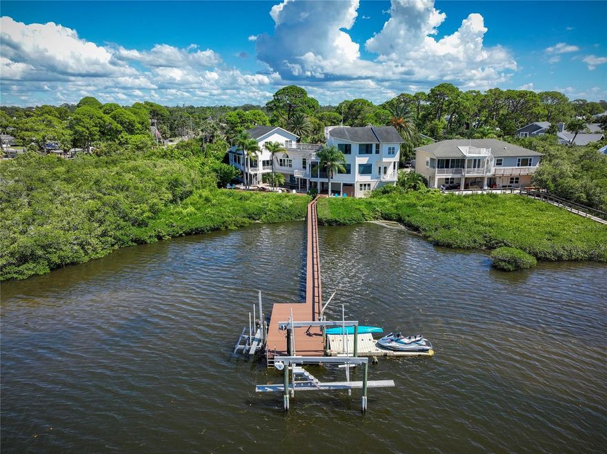 Discover the pinnacle of waterfront living in this extraordinary residence offering 5469SF of thoughtfully designed space. With 6 bedrooms, 5.5 bathrooms, and two luxurious primary suites, this home is perfectly tailored for multi-generational living. Nearly every room captures breathtaking water views, blending elegance and serenity at every turn.

Designed with versatility in mind, the home features two distinct wings joined by a remarkable custom, high-tech bookshelf that opens by key fob. Closed, it’s a sophisticated architectural statement; open, it reveals the West Wing with a formal living room, library/guest suite, large private office with extraordinary water views, elevator, and a dramatic staircase leading to the second primary suite. This third floor primary suite with elevator access offers westward water views,  a fully remodeled spa bath with soaking tub, walk-in steam shower, and dual vanities and dual walk in closets.

The East Wing is equally impressive, offering a fully renovated open-concept kitchen with custom two-toned cabinetry, expansive marble counters, Wolf appliances, double ovens, induction cooktop, and wine fridge. Expansive porcelain plank flooring, wood accents, custom iron railings, and designer chandeliers elevate the home’s style. Upstairs, three additional bedrooms—two with balcony access—offer sweeping water views and a beautifully renovated guest bath.

Outdoors, the lifestyle continues with ~2,200 sq. ft. of composite decking, a sparkling pool and spa, updated landscaping, and a new gas-heater for the hot tub. Boaters will appreciate the newly update composite dock with 13,000 lb. lift, floating dock for jet skis, and deep-water access to the Gulf. The  At day’s end, ascend to the rooftop deck for panoramic sunsets that capture the essence of Florida’s waterfront lifestyle.

Additional features include a 3-car garage, elevator servicing all floors, game room with pool bath, and numerous recent updates: New boat lift Motors (2025) New Composite Dock (2025) New AC Compressor and air handler (2024) new hot water heater (2024), front window replacement (2024), upgraded flooring, renovated bathrooms throughout the home,  custom staircase steps, new outdoor shower and even a sand pit fire-pit for relaxed evenings outdoors. Top this off with a new roof which will be replaced PRIOR to Closing!

Perfectly situated along scenic Sutherland Bayou and adjacent to Pop Stansel Waterfront Park, this home is zoned for top-rated schools including Ozona Elementary and Palm Harbor University High School. No leasing restrictions or HOA restrictions in place! AirBNB investors welcome!

Every detail has been carefully considered to deliver luxury, comfort, and a true waterfront lifestyle. Don’t miss your chance to experience this one-of-a-kind property—schedule your private tour today
