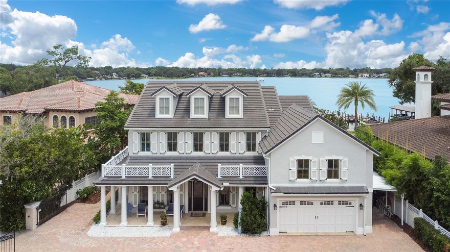 The Winter Park Chain is the context; the shoreline of Lake Minnehaha is the setting. A three-story, columned home opens with an honest, crafted tone: new low-profile concrete tile roof, operable cypress shutters with hand-forged hardware, Chippendale balustrades, and a beveled front door offering almost 6,200 sq. ft. curated for light, views, and everyday lake living. Inside, the home is bright and airy—sunlight does the work here. A direct foyer sightline leads you to a rear wall of French doors that draw in a calm, even glow of natural light across heart-of-pine floors and disciplined millwork: raised-panel wainscot, multi-step crown molding, and architectural beams. Those doors open to a full-length covered lanai; beyond, a heated saltwater pool and spa step down to a deep backyard and a private dock with a covered boat slip and adjoining lounge deck. The kitchen is built to perform so life feels easy. Morning coffee, weeknight pasta, Saturday crowds, it handles all of it. Sub-Zero refrigeration with additional refrigerator drawers, a Thermador six-burner gas range, two dishwashers, and a warming drawer. Granite counters surround a prep island with rinse sink; the peninsula takes the laptops and late plates. A dry bar with wine cooler ties to the dining room for effortless pours and keeps glassware close at hand. Just off the family room, the primary suite claims a quiet corner and opens to the lanai; coffee at sunrise, warm light at day’s end. A large custom walk-in closet answers storage; the bath finishes the suite with tumbled marble, Kohler fixtures, and a cast-iron vintage tub. At the center of the first floor, a deliberate service run keeps daily life organized: powder bath, temperature-controlled wine cellar, a straight sightline to the first of two laundry rooms and the garage entry ending at a private interior stair to a secluded in-law/guest suite with its own full bath. It’s independent, quiet, and ideal for long stays or live-in support. The main stair brings you to a second level arranged with intent. One wing holds three bedrooms around a shared bath. An office corridor carries you to the lake-view great room under a coffered ceiling; triple French doors open to the full-length upper veranda. Another bedroom on this wing enjoys its own veranda access with a full bath close by. Above it all, the third floor is a generous, flexible loft fit for a screening room, billiards or game lounge, studio, gym, or a collector’s library with practical storage tucked to the edges. Quiet systems match the craft: Cat-5 wiring, surround sound, central vacuum, and two laundry rooms. Recent updates keep the essentials current: new HVACs (2020, 2021) and a new dock (2024). Zoned for Maitland Middle and Winter Park High, this home is tuned to everyday rhythm: water out back, light throughout, spaces that work the way you live. From lanai shade to the last light on the lake, it delivers on its promise—an honest, crafted place where the architecture serves the life it keeps.