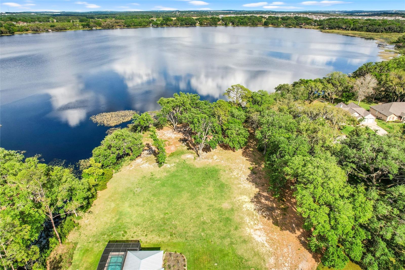 Discover the perfect canvas for your dream home with this exceptional property boasting 164 feet of direct lakefront and an additional 178 feet of canal frontage on the serene Groveland Chain of Lakes. Imagine waking up to panoramic views of the lake and enjoying your own private dock, ideal for boating and fishing enthusiasts. This rare offering is one of the few direct lakefront properties in the area, presenting an unparalleled opportunity to embrace the natural beauty of the surroundings. Spend your days biking along scenic trails and immersing yourself in nature’s splendor. Conveniently located just a short distance from the Florida Turnpike entrance and with NO HOA restrictions, this is your chance to visualize and create the home you’ve dreamed about for years. Don’t miss out on this unique opportunity to build your lakeside retreat!