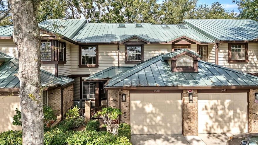 This spacious three-bedroom, two-and-a-half-bath townhome offers comfort, convenience, and an unbeatable location. Protected by a new metal roof and cooled by a newer A/C system, the home is ideally situated near the Pinellas Trail, Dunedin Causeway, Honeymoon Island State Park, and a variety of shopping, dining, and top-rated schools. You’ll enjoy being close to the beaches—without being in a flood zone.
Owners have the benefit of a private garage, with additional parking in the driveway and nearby guest spaces. Visitors enter through a charming gated front garden into the foyer, while owners can step in through the garage, passing a half bath, closets, and a large laundry closet before reaching the same welcoming entry. The bright, roomy kitchen features an eat-in dining area with a bay window overlooking the gated garden, plus a pantry, granite countertops, wood cabinetry, and stainless steel appliances. A breakfast bar with seating for four opens to the family room, where a fireplace adds warmth and character. French doors lead to the screened porch with tranquil views of the patio, gardens, pool, and tennis courts. The double-sided fireplace also enhances the living room, which is filled with natural light from bay windows and French doors that open to the same screened porch. The living room flows seamlessly into the dining area, highlighted by high ceilings and two skylights. Upstairs, brand-new luxury vinyl plank flooring runs throughout. The primary suite features a vaulted ceiling, a custom walk-in closet, and a spacious ensuite bath with new tall white cabinetry, dual sinks, a seated vanity area, and a large shower, ideal for two to get ready at once. All three toilets in the home have been recently replaced. Two additional bedrooms, both with built-in closet systems, are located across from the updated hall bath with new white cabinetry and a tub/shower combination. One bedroom includes its own private screened balcony. Both enjoy peaceful views of the pool, tennis courts, and spa at the far end of the beautifully maintained oak-filled courtyard.Homes like this, in locations like this, don’t last long. Schedule your private showing today.