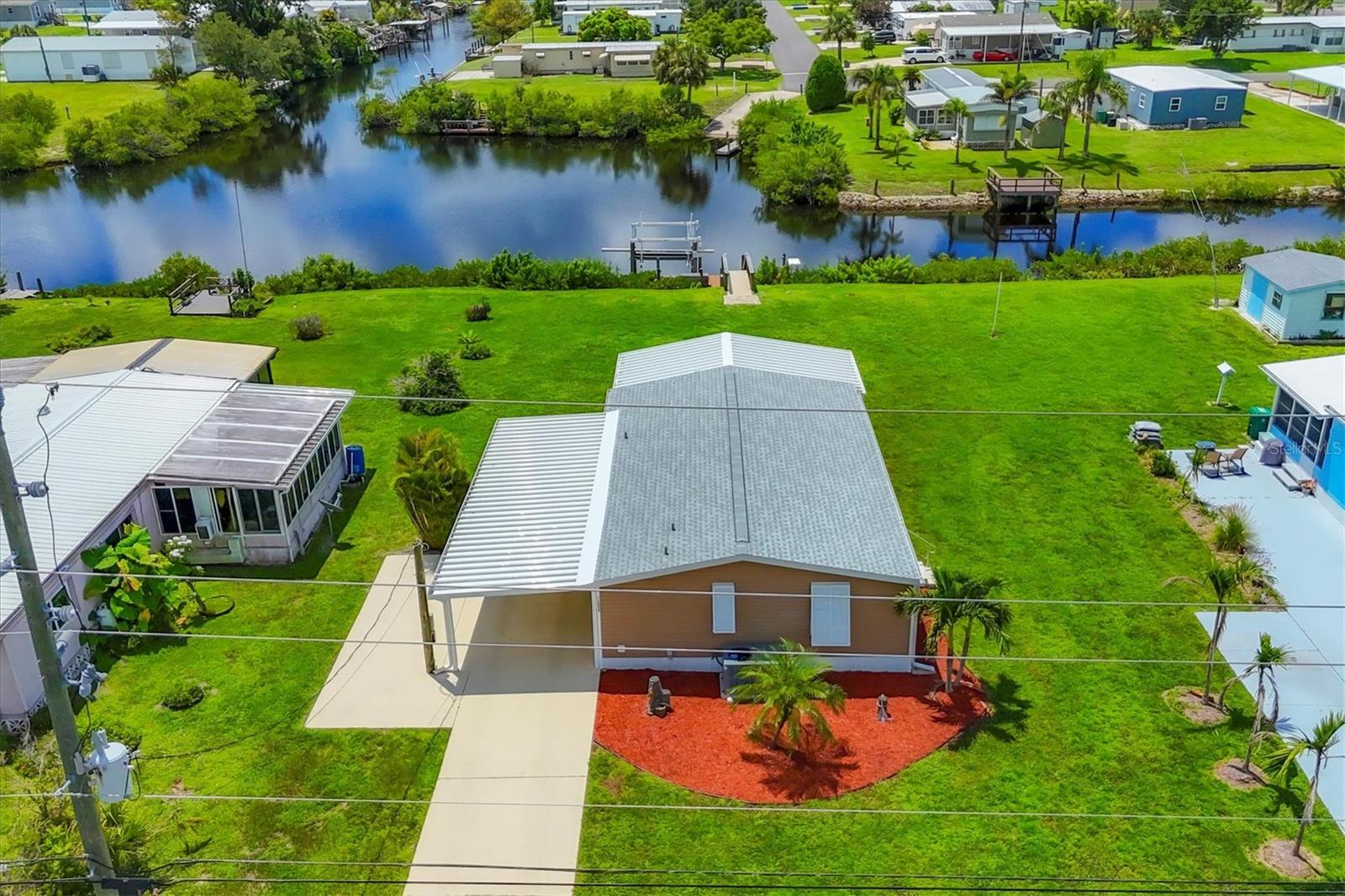 Boating before dawn. Sunsets before sleeping. Jump right into your boat and head out to open water right from your own backyard. Live your story or write your book in the comfort of this 3- bedroom, 2 bath, double wide mobile home on this stunning saltwater canal leading to the Gulf. The 16x28-6,000 lb. boat lift is just the perfect size and features a remote control for the lift, 2 water stations, a fish cleaning station and electricity. You will have great Peace of Mind having a NEW roof, NEW carport, NEW vapor barrier and NEW insultation. The home has many improvements such as freshly painted interiors, the 24x12 Florida room has a new COASTAL look with freshly painted beadboard walls, vinyl sliding windows, screens and Sunblock roll down shades as well as soothing indoor-outdoor carpet. Additional notable improvements are the BEAUTIFUL Pergo Outlast wood flooring in the living and bedroom areas. Easy to care for tile in the kitchen, indoor laundry room and bathrooms. New remote controlled ceiling fans in the Living and Primary rooms. The 10x12 outdoor shed has lighting and electricity and gives you plenty of room to store extra items. Just about every inch of this fabulous home has been touched up. Built in 1985, this 1040 SQ.FT., double wide home also comes with assumable flood insurance. Holiday Mobile Estates is now Manatee Cove, a friendly, active 55 plus community in the heart of Englewood surrounded by shopping centers, local restaurants, unique boutiques and only 5 minutes to Englewood Beach.