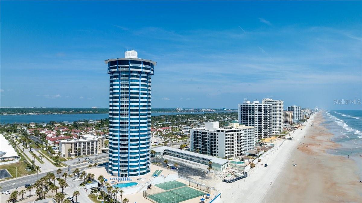 Wake each morning to sweeping ocean views from this beautifully renovated 11th-floor condo in iconic Peck Plaza, and end each day with a dazzling sunset from your private balcony. Unforgettable vistas stretch from the living room to both bedrooms, creating a constant connection to the sea. The interiors are tastefully appointed with a serene coastal palette, featuring a spacious living area with a wall-mounted flat-screen, pullout sofa, dining space, and ceiling fan. The primary suite offers a king bed, walk-in closet, private bath, and tranquil views, while the guest bedroom boasts two queen beds, ocean outlooks, and its own ceiling fan—comfortably sleeping up to eight guests.
Designed for both personal enjoyment and income potential, this fully furnished residence allows weekly rentals and comes with proven rental history and future bookings. Residents of Peck Plaza enjoy resort-style amenities including an oceanfront pool and spa, tennis courts, fitness center, social room, and the celebrated Top of Daytona restaurant crowning the building. Combining breathtaking views, turnkey readiness, and outstanding investment appeal, this is a rare opportunity to own a piece of Daytona Beach luxury living.