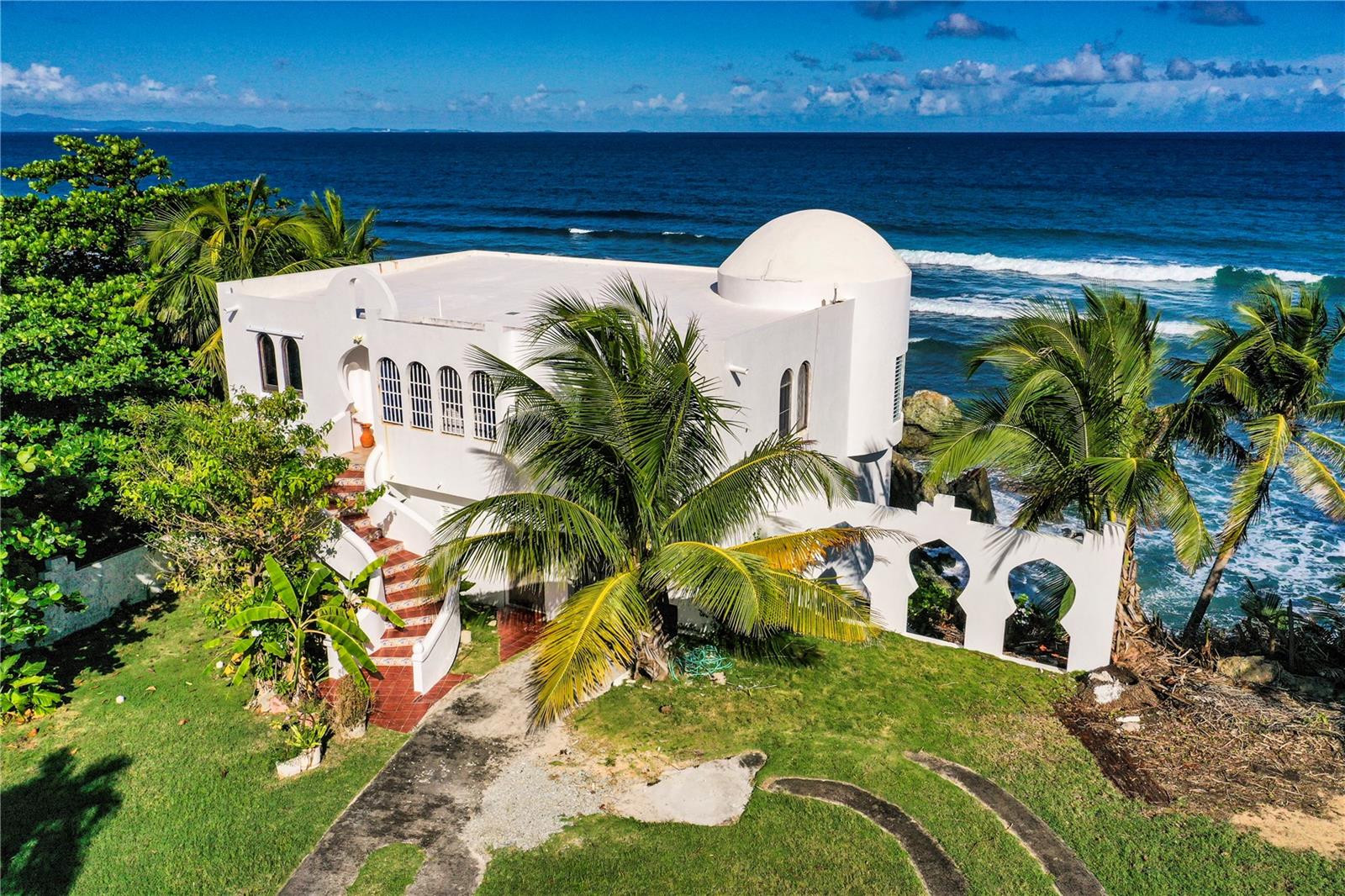 El-Maroc is an oceanfront estate in the privileged Bravos de Boston beach-side neighborhood of Vieques Island. Once in a generation opportunity, this sale represents the first time El-Maroc has ever been offered and is a one of a kind coastal home with Moroccan inspiration. The home is spectacularly sited on the cliffs at waters edge and could not be built here today. El Maroc is one of the most envied villa-estates on Vieques Island.
El-Maroc is sighted on a breathtaking oceanfront lot of almost 1/2 acre and features a home that transports you to the enchantment of Morocco, inspired by the family's unforgettable journeys to Morocco. Nestled along the pristine shores of La Chata Beach, this exquisite property is to be restored to a luxurious estate with the natural splendor of the ocean as your back yard.
The main house features three bedrooms, two bathrooms with two living areas, a library and two kitchens. The oceanside terrace is a wonderful retreat with waves rolling and crashing against the rocks below. This is a place to savor the ocean's raw beauty, to watch migrating whales breech in the distance, and to simply feel at home in the soothing sounds of the sea. This is also a favorite surfing beach so you can watch the action from the comfort of your home or grab your board and head out to catch a wave.
The Guest House has one bedroom and one bathroom with kitchen and living room. This is the perfect place for family members or guests to have an extended stay. The Guest House could also be used as short or long term rental for extra income.
While this wonderful home needs some updating the location of the home at water's edge could not be built today. This house sits comfortably on a rocky cliff protecting the house while also able to dip you toes in the water from your back yard. There is plenty of room to add a swimming pool and hot tub.
El Maroc is a once in a lifetime opportunity to create your own oceanfront retreat with your signature.