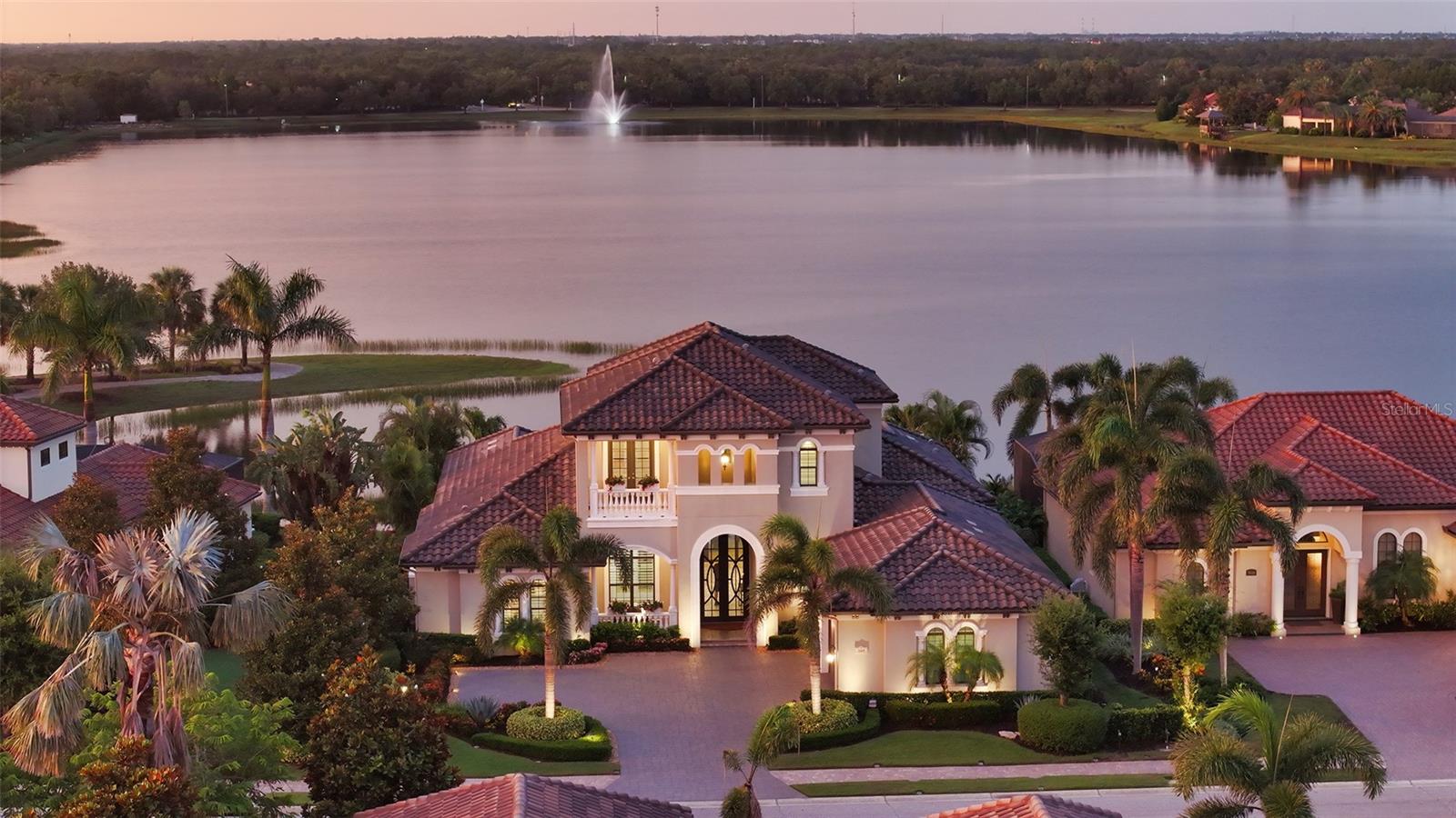 Unparalleled luxury and privacy await in this custom-designed Arthur Rutenberg home, perfectly situated in the gated community of Country Club East in Lakewood Ranch. From the moment you arrive, you'll be captivated by the stunning curb appeal, with impeccably upgraded landscaping, exterior lighting, and a stately presence that sets this home apart. Positioned on a premium homesite with unobstructed, panoramic long lake views, this residence offers a rare combination of elegance and seclusion.
Step inside to a sophisticated interior where thoughtful design meets modern convenience. The open living space is anchored by pocketing sliders that lead to an exceptional outdoor oasis featuring a resort-style infinity-edge pool and spa with fire bowls and water feature, wood-paneled ceilings, a covered lanai with a cozy outdoor fireplace seating area, an outdoor kitchen, and convenient access to a cabana bath—ideal for both relaxing and entertaining year-round. Inside, the gourmet kitchen is a dream for any chef, complete with granite countertops, a marble stone backsplash, built-in oven, cooktop, large island with seating and storage, and a walk-in pantry.
The main floor features a luxurious primary suite overlooking the lake, as well as a private guest suite and a dedicated office. Upstairs, two additional guest suites and a spacious bonus room with a wet bar open to a rear balcony, creating the perfect retreat for family or guests. Throughout the home, you'll find high-end finishes including porcelain tile and engineered hardwood floors, solid wood interior core doors, as well as advanced features such as whole-house Control4 smart home technology, whole-house audio, central vacuum, and a dedicated wine area for entertaining.
Built for comfort and efficiency, the home includes a whole-house generator, impact glass windows and doors, energy-efficient Icynene insulation, and ample storage throughout. The garage is equally impressive with split AC, an EV charger, and extensive built-in storage solutions.
This is a rare opportunity to own one of the most thoughtfully designed and immaculately maintained homes in Country Club East, where luxury meets lifestyle in the heart of Lakewood Ranch. Schedule your private showing today and experience the serenity, sophistication, and smart living this exceptional property offers.