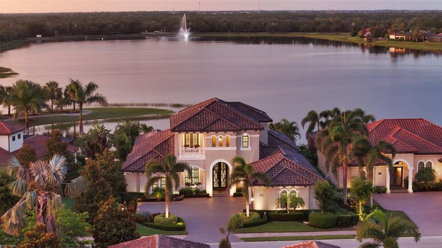 Unparalleled luxury and privacy await in this custom-designed Arthur Rutenberg home, perfectly situated in the gated community of Country Club East in Lakewood Ranch. From the moment you arrive, you'll be captivated by the stunning curb appeal, with impeccably upgraded landscaping, exterior lighting, and a stately presence that sets this home apart. Positioned on a premium homesite with unobstructed, panoramic long lake views, this residence offers a rare combination of elegance and seclusion.
Step inside to a sophisticated interior where thoughtful design meets modern convenience. The open living space is anchored by pocketing sliders that lead to an exceptional outdoor oasis featuring a resort-style infinity-edge pool and spa with fire bowls and water feature, wood-paneled ceilings, a covered lanai with a cozy outdoor fireplace seating area, an outdoor kitchen, and convenient access to a cabana bath—ideal for both relaxing and entertaining year-round. Inside, the gourmet kitchen is a dream for any chef, complete with granite countertops, a marble stone backsplash, built-in oven, cooktop, large island with seating and storage, and a walk-in pantry.

The main floor features a luxurious primary suite overlooking the lake, as well as a private guest suite and a dedicated office. Upstairs, two additional guest suites and a spacious bonus room with a wet bar open to a rear balcony, creating the perfect retreat for family or guests. Throughout the home, you'll find high-end finishes including porcelain tile and engineered hardwood floors, solid wood interior core doors, as well as advanced features such as whole-house Control4 smart home technology, whole-house audio, central vacuum, and a dedicated wine area for entertaining.

Built for comfort and efficiency, the home includes a whole-house generator, impact glass windows and doors, energy-efficient Icynene insulation, and ample storage throughout. The garage is equally impressive with split AC, an EV charger, and extensive built-in storage solutions.

This is a rare opportunity to own one of the most thoughtfully designed and immaculately maintained homes in Country Club East, where luxury meets lifestyle in the heart of Lakewood Ranch. Schedule your private showing today and experience the serenity, sophistication, and smart living this exceptional property offers.