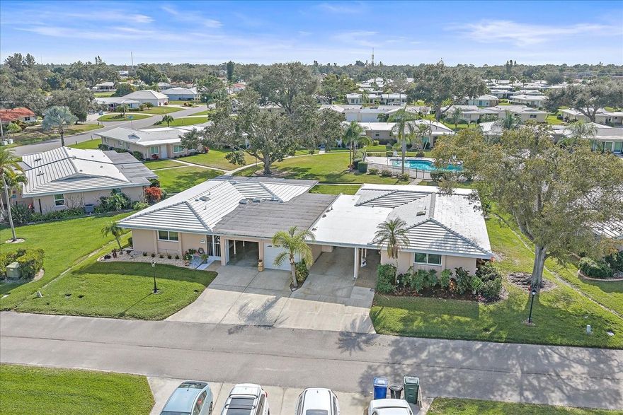 Ready to retire in Sarasota? Welcome to Village Green in South Gate—truly the heart of Sarasota. LESS THAN 10 MINUTES TO SIESTA KEY, DOWNTOWN SARASOTA, AND THE HIGHWAY, PLUS JUST 15 MINUTES TO THE AIRPORT AND UTC, this location puts you right in the center of it all while still enjoying a peaceful 55+ lifestyle. THIS HOME HAS NEVER FLOODED and offers A BRAND NEW CERAMIC TILE ROOF, providing low-maintenance living for years to come.

This is ONE OF THE LARGEST VILLAS IN THE COMMUNITY, featuring a TRUE OVERSIZED LAUNDRY ROOM. NEW FLOORING throughout. Abundant STORAGE. The updated kitchen is a showstopper with NAVY BLUE CABINETRY, STAINLESS STEEL APPLIANCES, AND QUARTZ COUNTERTOPS, plus TONS OF COUNTER SPACE and a spacious layout that makes cooking and entertaining a dream. There is AN EAT-IN KITCHEN AREA PLUS A FORMAL DINING SPACE, offering flexibility for everyday living and hosting.

The OPEN-CONCEPT LIVING ROOM IS FILLED WITH NATURAL LIGHT, creating a bright and welcoming feel. Just off the living area is a FLORIDA ROOM OVERLOOKING THE COMMUNITY POOL, perfect for a home office, craft room, or extra lounge space, along with A SCREENED-IN LANAI so you can enjoy the Florida sunshine bug-free.

The TWO SPACIOUS BEDROOMS ARE LOCATED DOWN A SEPARATE HALLWAY FOR PRIVACY AND QUIET. A true PRIMARY SUIT with WALK In CLOSET. With TWO FULL BATHROOMS—ONE WITH A WALK-IN SHOWER AND THE OTHER WITH A TUB— you have the best of both worlds. HURRICANE-GRADE WINDOWS IN THE MAIN LIVING AREAS add peace of mind, and if you’ve been wanting a garage, THE CARPORT IS READY—JUST ADD A DOOR.

Step outside and the COMMUNITY POOL IS PRACTICALLY IN YOUR BACKYARD, feeling like your own private oasis. Enjoy a LOW-MAINTENANCE LIFESTYLE WITH GROUNDS MAINTENANCE INCLUDED, a WELL-FUNDED COMMUNITY with rumored future fee decreases, and VILLAGE GREEN GOLF CLUB JUST STEPS AWAY for the golf enthusiast. This is Sarasota 55+ living at its best—schedule your private showing today.