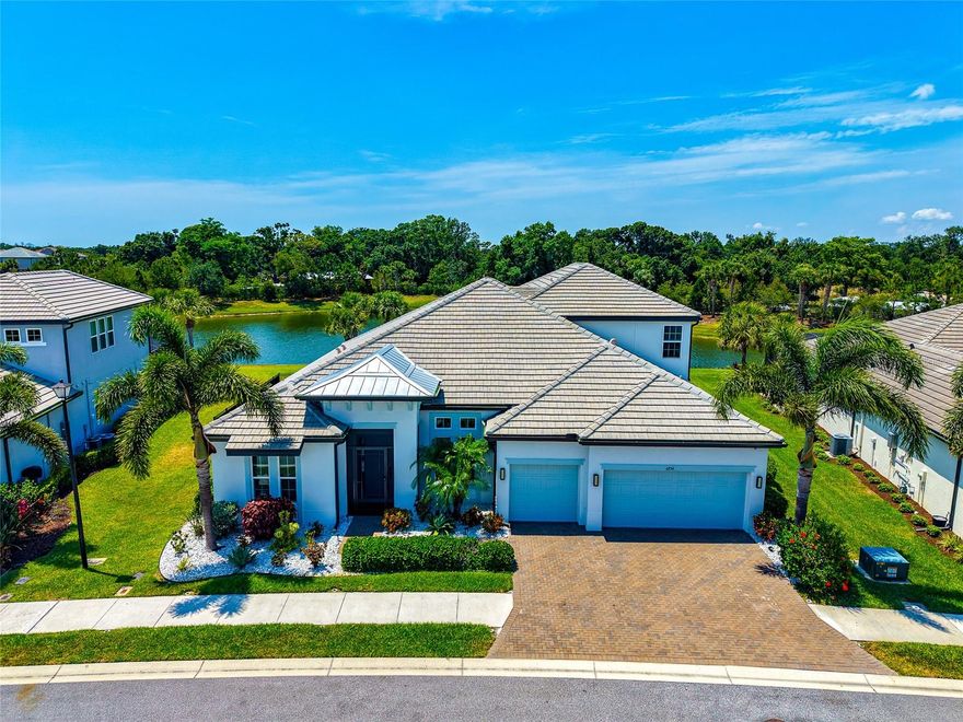 This meticulously upgraded home blends modern coastal elegance with resort-style indoor and outdoor living.
From the moment you enter, the home makes a statement with soaring ceilings, designer finishes, and expansive open-concept living spaces filled with natural light. The stunning great room features a custom-built electric fireplace with illuminated built-in shelving, creating a sophisticated focal point for entertaining or relaxing evenings at home. Rich custom woodwork accents in the tray ceilings of the primary suite, living room, and dining area add warmth, texture, and craftsmanship rarely found in newer construction homes.

The chef’s kitchen is both beautiful and functional, showcasing an oversized quartz island, premium cabinetry, gas cooktop, under-cabinet lighting, wine refrigeration, custom coffee bar, and an effortless flow into the dining and living areas.
The spacious primary retreat offers serene lake views, a spa-inspired bath with dual vanities, freestanding soaking tub, oversized walk-in shower with rain shower head, and an expansive custom walk-in closet thoughtfully designed for both luxury and organization.

Additional living spaces include a dedicated office, ideal for working remotely in style, and an oversized bonus/game room that offers endless flexibility for a media room, fitness space, playroom, or guest retreat.
Designed for elevated living and effortless entertaining, the home also features an integrated speaker system throughout the office, primary suite, living room, kitchen, bonus room, and outdoor pool deck area, creating a seamless indoor-outdoor audio experience. A security system, whole-home water softener, and whole-home Generac generator provide exceptional comfort, convenience, and peace of mind year-round.
Step outside into a private resort-style sanctuary where luxury Florida living truly comes to life. The expansive panoramic screened lanai frames breathtaking lake views while creating an atmosphere of total privacy and tranquility. The heated pool and spa feature elegant modern lines, sun shelf lounging areas, and expansive paver decking designed for both relaxation and entertaining.
The custom outdoor grilling area transforms the outdoor living space into a true extension of the home, ideal for sunset dinners, weekend gatherings, or a place to enjoy a morning cup of coffee. As dusk settles, the programmable exterior lighting and illuminated pool environment create a breathtaking ambiance worthy of a luxury resort.
This home delivers the perfect balance of sophistication, comfort, and Florida luxury living.   Schedule your showing today!!