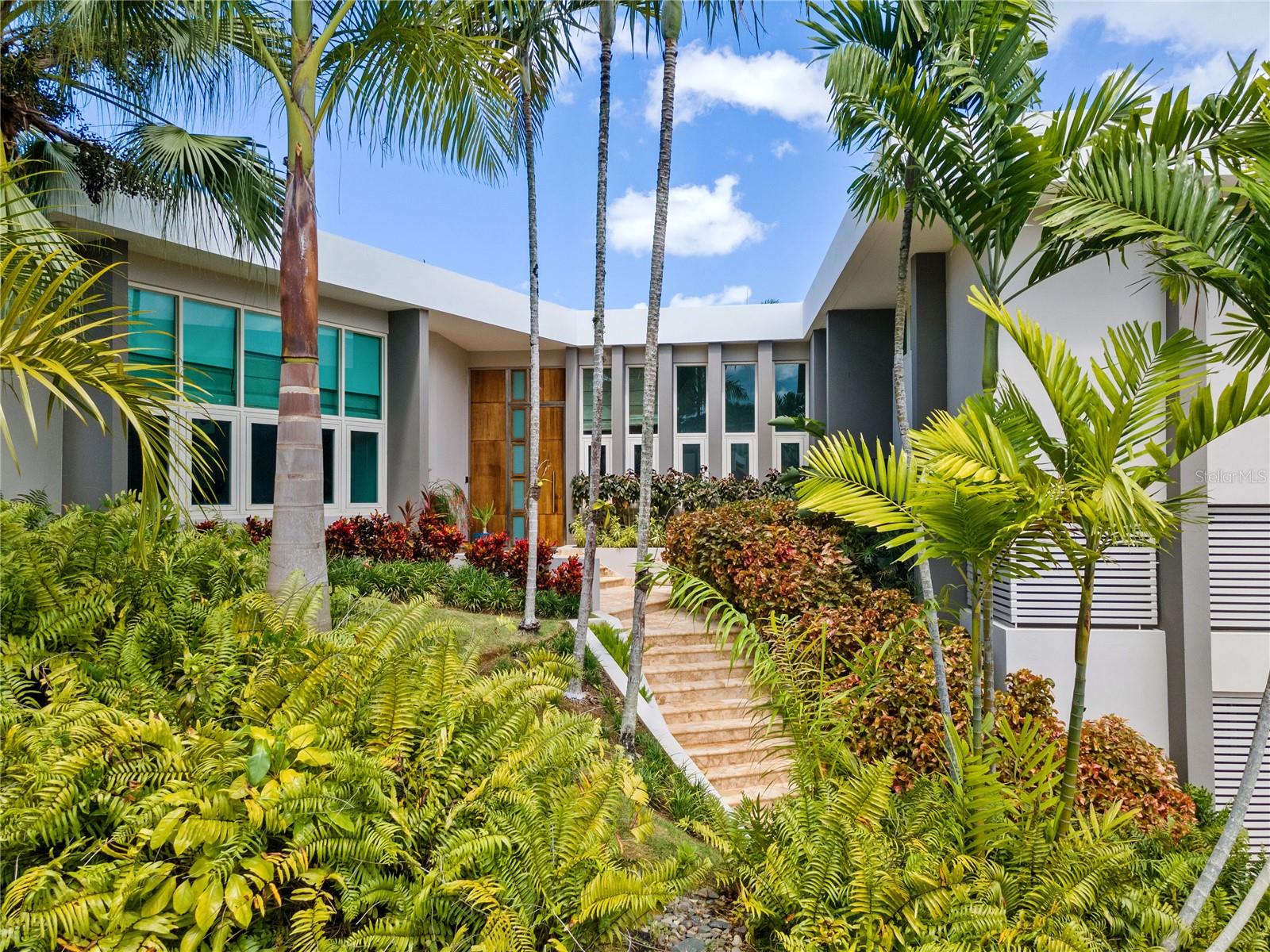 Welcome to a contemporary architectural gem, discreetly nestled on a private cul-de-sac in the coveted Garden Hills neighborhood of Guaynabo. This expansive property situated within a generous 1,245 square meter lot, showcases a home that embodies resort elegance and tranquility, offering an impressive 4,100 square feet of living space.
This retreat exudes an ambiance of privacy and relaxation, thoughtfully designed across three levels, offering 4 bedrooms, 4 full baths, 2 half baths, a home office, and a guest studio apartment.
Upon entry, the main level impresses with its skylight-adorned foyer, revealing a spacious living room that opens to an interior patio. The well-appointed open kitchen, with its brilliant design, granite countertops, modern appliances, and ample cabinetry, effortlessly connects to the formal dining room, family room, home office, and a powder room.
From the dining area and kitchen there is a continuous transition to the expansive outdoor terraces, where one can appreciate sweeping views of the lush and verdant landscape offered by its natural surroundings. A spacious kitchen and dining area with folding glass windows lead to an inviting terrace that overlooks a striking waterfall, pool and patio.
The residence features refined marble floors, recessed lighting, and an air of sophistication that characterizes each space. Floor-to-ceiling windows accentuate the spacious and bright rooms. Abundant natural light gracefully illuminates every corner of the residence, creating a warm and peaceful ambiance from the moment you step in. Boasting a cascade-style pool, a tranquil koi pond, an exterior dining area, wet bar, barbecue grill, and a spacious covered terrace, the home offers an enviable outdoor oasis meticulously designed for seamless entertaining.
The property caters to a discerning crowd with an appreciation for design seeking relaxed resort living. By effortlessly integrating the surrounding natural beauty into its architectural design, this home is ideal for hosting grand-scale gatherings.
Notable equipment included with the purchase: central air conditioning, 5 inverter units, a solar water heater, 400 galons cistern, a 45K power generator, and ample storage closets.
Garden Hills Sur is recognized as a premier community within Guaynabo, offering one of Puerto Rico's most sought-after locations. Located just 15 minutes from San Juan, this community offers private access for residents to Torrimar Park, sports center that features baseball and soccer fields, along with basketball and tennis courts. Adjacent to Baldwin School and in proximity to numerous shopping venues, including the renowned San Patricio Plaza, this residence harmoniously balances suburban comfort with the conveniences of city living.
Discover a lifestyle of unparalleled refinement in this Garden Hills masterpiece—a contemporary sanctuary where elegance, space, and natural beauty converge to create a truly exceptional living experience.
(Property also available for Rent - $13,000.00)