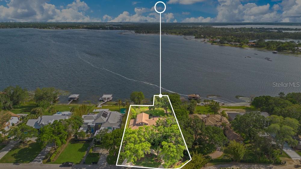 This exceptional lakefront home is located on The Butler Chain of Lakes with 137 feet of pristine shoreline and is situated on almost one dry acre. At first glance you will immediately fall in love with this beautiful custom home boasting amazing panoramic views and nightly Disney fireworks. The circular paved drive flanked with mature oak trees welcome you home to a covered porch and an 8-inch-thick solid cedar entry door with artisan leaded glass. The great room definitely adds to the “wow factor” with its soaring 23’ cathedral ceilings highlighted by a Tennessee river rock fireplace, and the crown jewel formal dining room with large, picturesque windows overlooking the stunning vistas. The majority of the living space, including all the bedrooms, are conveniently located on the main level. Your fully equipped kitchen includes solid wood cabinetry, granite countertops, Sub Zero refrigerator, Thermador gas cooktop with exhaust, Bosch double ovens, wet bar, walk-in pantry, and breakfast area with spectacular views. Primary suite is spacious with its own screened in lanai, spa like bath including a shower, jetted tub, dual vanities, and three walk-in closets. Secondary bedrooms are all generously sized with ample closet space and bathrooms including a steam shower. The backyard space is extraordinary with mature landscaping, flowers, and its own motorized screened in lanai including a summer kitchen fit for any chef with a pizza oven, prep area, grill, refrigerator, TV, pool, heated spa, and gas firepit. The southern position of the backyard gives you the freedom to enjoy all those memorable get-togethers and cool lake breezes without the strong afternoon sun. The custom floor plan accentuates the lake lifestyle with most of the home taking full advantage of the lakeview. The partially enclosed boat dock with a boat lift and side jet-ski lift is a rare gem itself since it is grandfathered in. Other notable upgrades include newer doors & windows and a tile roof. Adding to the home’s appeal, the Lakes neighborhood has its own community boat ramp and tennis courts. You get to live in Windermere on the famed Butler Chain of Lakes without the traffic. Major roads, highways, great schools, shopping, and restaurants are just a five-to-ten-minute drive from the property. This rare well-built custom lakefront home is waiting for you! Be sure to click on the virtual tour links.