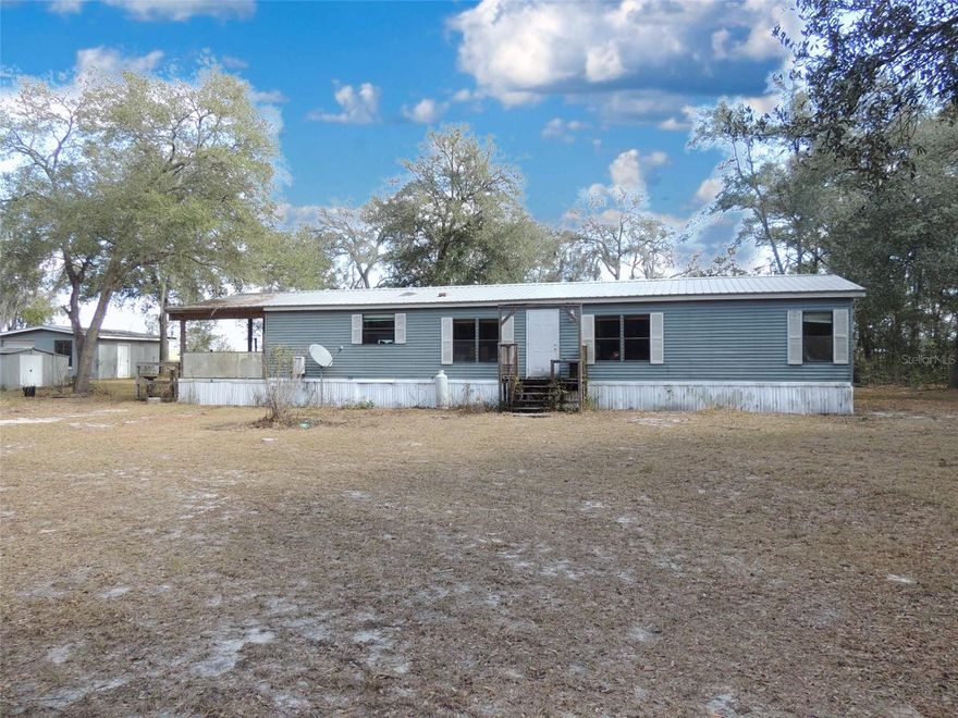 PURE COUNTRY LIVING ON OVER 5 ACRES in MORRISTON, FLORIDA. Experience the freedom of wide-open spaces with this 3 bedroom, 2 bath manufactured home set on 5.1 scenic acres in Morriston. Offering 1,620 square feet of comfortable living area, this property blends practical upgrades with the peaceful beauty of true North Central Florida country living. Shaded by mature, sprawling oak trees, the homesite provides a welcoming setting from the moment you arrive. The property is fully perimeter fenced with additional partial cross-fencing, making it ideal for animals, gardening, or creating separate use areas across the acreage. A vinyl fencing along the road adds curb appeal, while the expansive land offers plenty of room to roam, work, or relax in total privacy. The home features a durable metal roof, skylights that brighten the kitchen and primary bathroom with natural light, and a tankless LP gas water heater for efficient, on-demand hot water. Outdoor living is just as inviting with a generous 12' x 27' side deck—perfect for morning coffee, evening gatherings, or unwinding under the oaks. For those needing space for projects or storage, the property includes a concrete block detached garage and a separate 24' x 12' workshop, offering flexibility for hobbies, equipment, or small business use. 

If you’ve been searching for room to spread out while still being within reach of nearby towns, this Morriston acreage delivers the ideal blend of comfort, function, and rural charm. Make the move to pure country living and enjoy the space, privacy, and lifestyle you’ve been dreaming of.