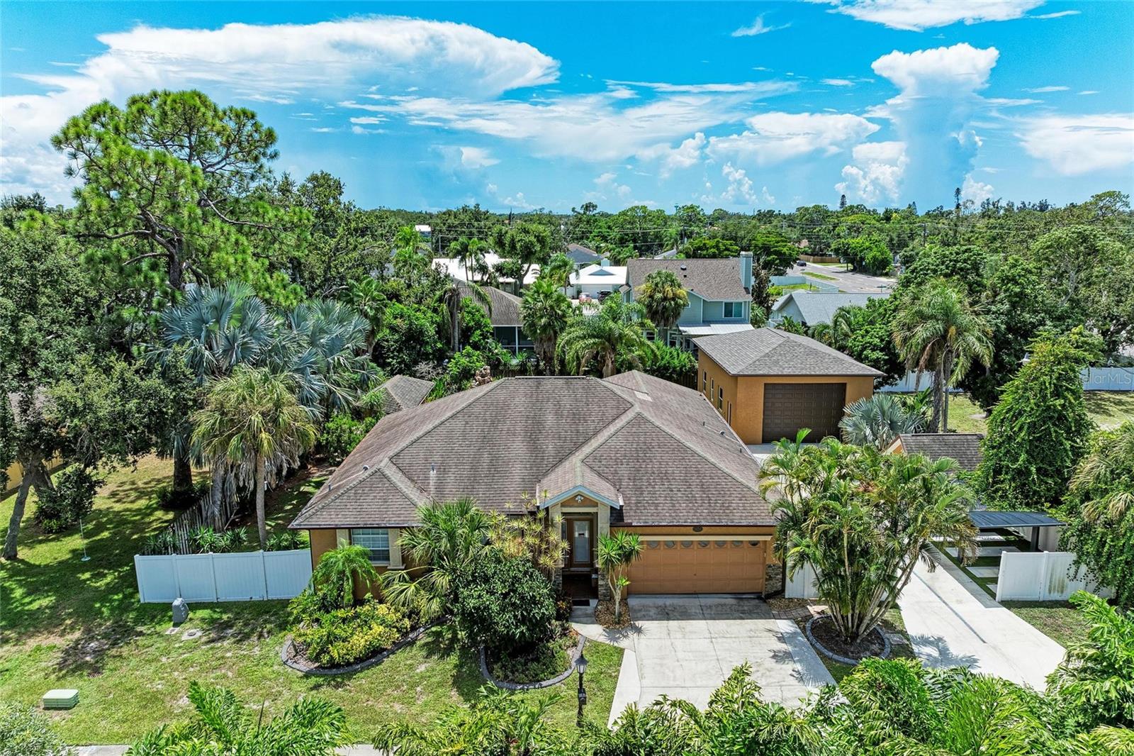 Why go on vacation when you live in this tropical retreat? This spacious home is an entertainer’s paradise with luxurious living both inside and out. As you enter, you'll immediately notice the modern finishes, from the sleek kitchen cabinets to the stylish light fixtures. The kitchen is a chef’s dream with stone countertops and stainless steel appliances. Just off the kitchen, you'll find an indoor laundry room with a newer LG washer and dryer set. The home is designed for comfort and efficiency, with a new HVAC and water heater both installed in 2022. The main living area features tall tray ceilings, and the abundance of natural light streaming through the sliding doors creates a bright, open atmosphere. The primary bedroom is a true retreat, offering walk-in closets and a beautifully renovated ensuite bathroom with a soaking tub, a separate standing shower, and dual vanities—the perfect place to unwind. For added privacy, the opposite side of the home offers three guest bedrooms with newer carpet, and a guest bathroom that also serves as a convenient pool bath, with direct access to the pool deck. Outdoors, this home truly shines with a saltwater heated pool featuring a waterfall, an outdoor kitchen, and a cozy fireplace for those cooler evenings. The travertine deck and outdoor shower complete this private oasis, while the dual carports for jet skis (or other recreational vehicles) and a separate RV garage offer ample space for all your toys. The home even has a separate well for irrigation, ensuring your lush tropical landscaping thrives year-round. Whether you're relaxing in the serene pool area, cooking up a meal in the outdoor kitchen, or enjoying the modern comforts of the interior, this home has everything you need and more! All of this in a prime location on a private road near shopping and award-winning beaches.