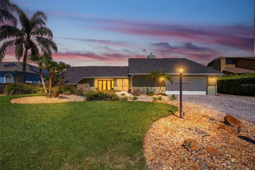 Wake up to stunning sunrises and wide water views, and unwind each evening with breathtaking sunset reflections over Lake Saxon—this 4-bedroom, 4-bath lakefront pool home offers a Florida lifestyle that’s both rare and unforgettable. Tucked away on a quiet cul-de-sac with 97 feet of frontage on an 83-acre private ski lake, this 3,202-square-foot residence is designed for relaxed living and effortless entertaining. A paver driveway and walkway lead to double glass entry doors, opening into a striking foyer with decorative tile inlay, plantation shutters, and refined architectural details. Inside, vaulted ceilings with exposed beams, arched openings, and decorative columns with wood caps create a sense of timeless character throughout. The formal living room impresses with soaring ceilings, exposed beams, and a wet bar with granite countertops—an inviting space for gathering—while sliding glass doors open seamlessly to the outdoor living area. A separate formal dining room provides an elegant setting for entertaining, and the family room centers around a wood-burning fireplace with a wood mantle and custom shelving, offering warmth and comfort. The kitchen is a true showpiece—beautifully designed with tall cabinetry topped with crown molding, built-in pantries, granite countertops, and a tile backsplash accented by a decorative bridge over the sink. Recessed lighting enhances the custom feel, while the center island features a premium Viking cooktop with a vent hood and pendant lighting above. Custom wood paneling conceals the refrigerator and dishwasher for a refined, cohesive look. The U-shaped layout maximizes prep space, with windows overlooking the lanai and pool, creating a seamless connection to outdoor living. The primary suite is a private retreat with exposed beams, direct lanai access, a large walk-in closet plus an additional closet, and a spa-style bath completed in 2025. Dual vanities, a freestanding soaking tub, and a tiled walk-in shower with both rain and handheld fixtures create a space designed for relaxation. Outdoor living is where this home truly shines. The screened lanai features a fully equipped outdoor kitchen with a built-in propane grill, vent hood, and sink, all overlooking a large geometric pool and expansive paver deck. Beyond the screen enclosure, additional paver space extends the entertaining area—perfect for gathering and taking in the lakefront setting. A landscaped paver walkway leads to a private dock with electric davits, providing easy access to Lake Saxon for boating, water skiing, or simply enjoying the open water. Additional highlights include a 2022 roof, dual A/C systems (2019, serviced 2026), water heater (2025), composite deck (2025), pool pump (2023), resurfaced pool (2018), hurricane shutters, a laundry room with cabinets and sink, and an expanded driveway with a 2-car garage for extra parking. The home also features a dedicated pool bath, outdoor storage room, and attic space with standing room. Located in Lake Padgett Estates, residents enjoy exclusive access to multiple private lakes, including Lake Padgett, Lake Saxon, East Lake, and Lake Joyce, along with private parks, boat ramps, and picnic areas—all reserved for residents and their guests, with no HOA or CDD. This is more than a home—it’s a lakefront lifestyle defined by space, privacy, and the ability to enjoy every day like a getaway.