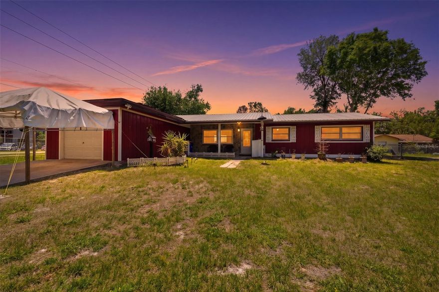 One or more photo(s) has been virtually staged. Charming farmhouse-style home on a corner lot with a metal roof, inviting front porch, and a spacious backyard complete with a greenhouse, large matching shed, and mature trees--perfectly located just steps from Crystal River High School. This 3-bedroom, 2-bath home offers a flexible layout, unique character, and a one-car garage with workshop for added functionality. From the moment you arrive, the home's red exterior, stone accent wall, and covered front porch create a welcoming first impression, offering the perfect spot for a table and chairs to enjoy the outdoors. A glass-paneled front storm door allows you to let in natural light while keeping the interior cool and comfortable. Inside, the living room features plush, well-maintained carpeting, a built-in bookcase, and a large front-facing window that brings in natural light. A high wall cutout near the ceiling connects visually to the kitchen, adding architectural interest while maintaining privacy between spaces. The dining area sits just beyond and features sliding glass doors that open to the rear patio, creating an easy indoor-outdoor flow. The kitchen offers decorative linoleum flooring, a mix of white upper cabinetry and coordinating lower cabinets, and a double sink positioned beneath a window overlooking the backyard. A combination of stone and tile backsplash adds texture and charm to the space. Just off the dining area, a large flex room provides so many options-currently used as an office, it features wood-paneled walls, multiple windows, matching carpet, and even a second refrigerator that conveys. The primary suite includes terrazzo flooring, multiple windows, a walk-in closet, and an ensuite bathroom with a step-in shower and single vanity. Two additional bedrooms also feature terrazzo floors, built-in closets, and natural light, while the guest bathroom showcases vintage charm with retro pink tile, a coordinating sink, a tub/shower combo with sliding glass doors, and a unique folding mirror. Additional highlights include an interior laundry room with the water heater and electrical panel, a security system, and a one-car garage equipped with built-in shelving and a dedicated workshop area. Step outside to enjoy the backyard, where you'll find a patio for relaxing or entertaining, a greenhouse for gardening enthusiasts, and a large storage shed that matches the home. A chain-link fence lines the rear of the property, and the corner lot provides added space and privacy. With its character, functionality, and unbeatable location just across the street to Crystal River High School, this home offers both convenience and charm.