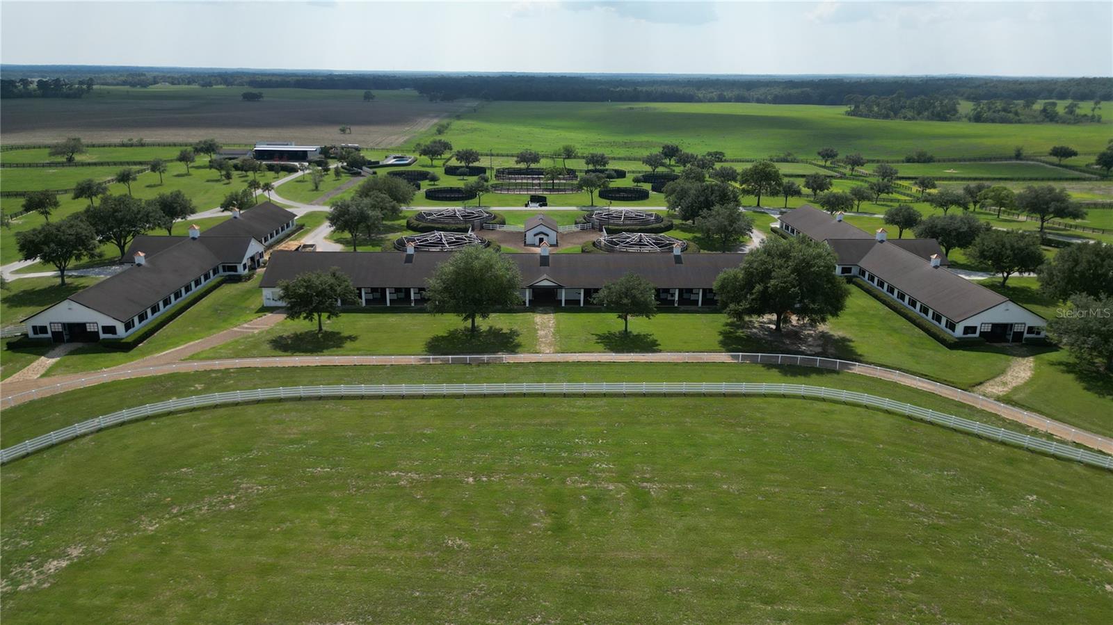 Under contract-accepting backup offers. This stunning 244.23 +/- acre horse training facility provides a truly turnkey equestrian experience! Nestled in NW Marion County, it's conveniently located just 10 miles from the World Equestrian Center and 10 miles from OBS Sales.
The facility boasts six barns with a total of 198 stalls, including two spacious 40-stall center aisle barns, a 38-stall shed row barn, a 24-stall shed row barn, a 30-stall shed row barn, and a 26-stall shed row barn. With versatility to accommodate any discipline, this property presents exceptional training opportunities on dirt and turf surfaces.
The facility features a professionally designed irrigated 1 +/- mile dirt racetrack and a 7/8 mile +/- turf track, ensuring optimal conditions for training while offering a viewing stand for spectators to enjoy the action. Watching Park Farm is truly a horse trainer's paradise, equipped with all the essential amenities for a successful equestrian operation.
Among the remarkable facilities is an equestrian swimming pool complete with a deck and secure PVC fencing for safety, (7) European walkers, (12) round pens, (3) riding arenas, (42) lush green paddocks, automatic waterers, an office, (2) workshops/storage buildings, a gated entrance, underground piping for water/sewer lines, and ornamental landscaping.
The entire property is secured with 4 and 5-board fencing and offers picturesque building sites to construct your dream home overlooking the farm. The equestrian facilities are first-rate, designed to support top-quality training for thoroughbreds or any breed of your choice. The farm also boasts a rich legacy of graduates, which includes 1 horse of the year, 7 Eclipse champions, 2 Kentucky Derby winners, 3 Preakness winners, 1 Belmont winner, 9 Breeders Cup winners, 43 individual Grade 1 winners, and a vast number of Grade 2 & Grade 3 winners.