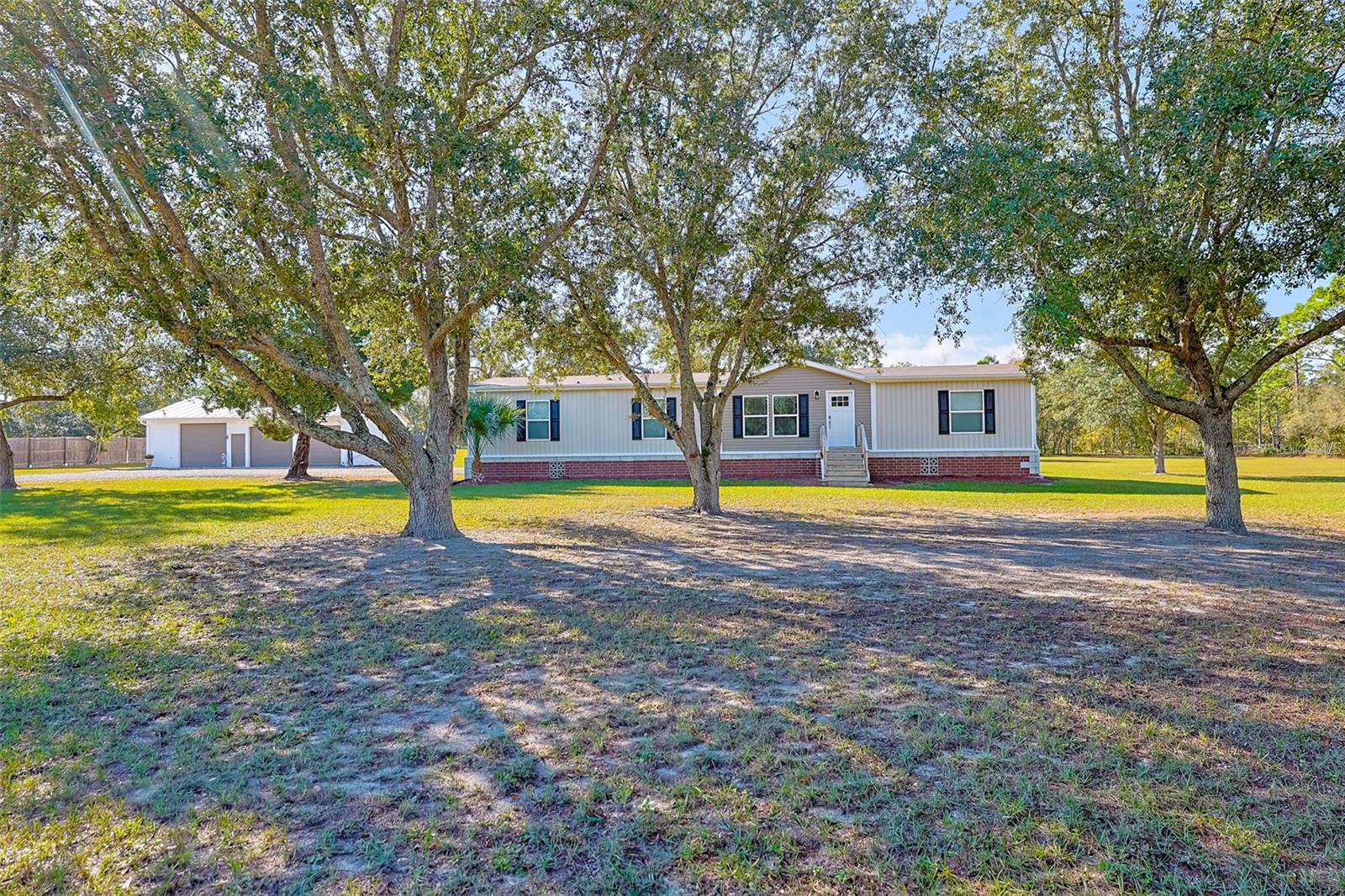 Welcome home to your Freedom Retreat! Enjoy freedom from electric, water, and sewer bills, freedom from HOA or CDD fees. This beautiful 2021 built manufactured home offers 4 bedrooms, 2 full baths, and over 1,900 sqft of living space. The property shines with incredible curb appeal, featuring block & brick accented skirting, neatly landscaped and manicured grounds and a canopy of mature shade trees creating a warm and inviting first impression. Check out these upgrades!!! This beautiful Moroccan Floorplan offers LED lighting throughout, granite countertops in kitchen with touch control farm sink, ball bearing drawer glides on all cabinets, walk-in closets with extra shelving, built in entertainment center shelving off the floor for easy cleaning and a spacious primary bedroom with large bath and dual vanities, an updated well and septic system, 36 brand new solar panels paid in full ($11K upgrade), custom block and brick decorative skirting with footer ($9K upgrade) and a spacious screened & covered lanai for all of your outdoor entertainment needs. Need extra space for storage? Check out the spacious 30' x 40' (1200sqft) barn with power and water. This awesome barn has LED lighting throughout, 100 amp breaker panel, 50 amp RV/camper power outlet on the side of the barn, an 8 foot door with electric opener, a second 8' x 8' door and a third 9' x 9' roll up doors,  outdoor dusk to dawn lighting to light up this amazing property and 5 outdoor security cameras. The beautiful home sits on 2.7 acres with plenty of room for a garden, pets and outdoor toys. This property also comes with 13 chickens and an automated coop with power and water. Whether you’re looking to start a homestead or simply enjoy peaceful country living, this property offers the perfect blend of comfort, self-sufficiency, and style! It’s just a great home for an even better price!