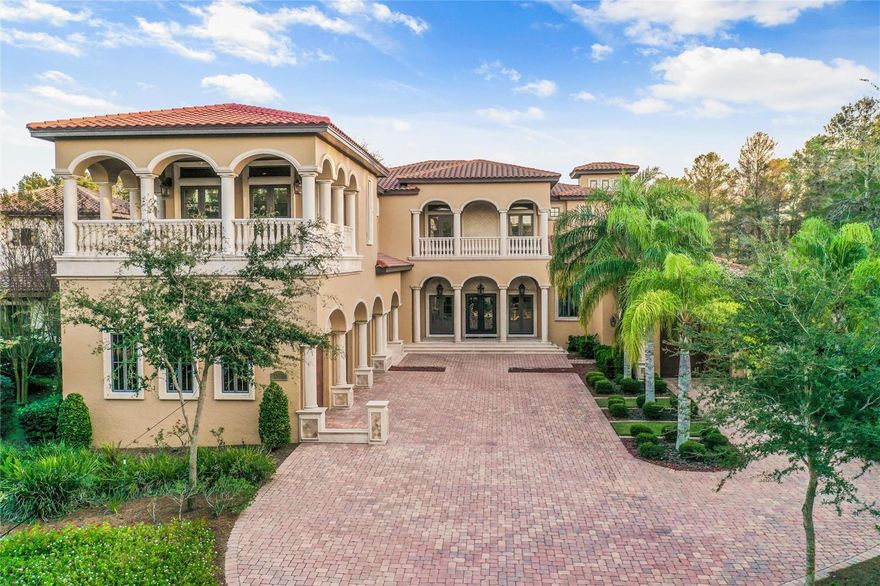 Welcome to this architectural masterpiece nestled in the stunning Bella Collina. This exceptional residence boasts 6 bedrooms and 7.2 baths, embodying the pinnacle of high-end living. The pool area is a haven of tranquility, offering a perfect blend of privacy and natural beauty. A sprawling lanai, adorned with various sitting and dining areas, surrounds the huge pool, complete with a relaxing fire pit and cascading waterfall. The expansive summer kitchen is complemented by a step-down area, perfect for serving cocktails to those seated on built-in stools within the pool. Craftsmanship is evident in every detail of this property, from the exceptionally detailed wood ceilings to the flowing wood floors. The house is strategically set back, featuring 4 front-drive garages and an additional 3 at the rear. Upon crossing the threshold of the double front doors, you are greeted by spectacular barrel ceilings, pillars, and captivating views of the oasis beyond. The open-plan design seamlessly connects the kitchen, dining area, and cathedral-height living room, with sliders opening to the patio. The kitchen is a chef's delight, equipped with top-of-the-line Wolf appliances, including 3 ovens. Custom cabinetry, granite surfaces, and a breakfast bar complete this culinary haven. The office exudes sophistication with maple wood details and an inlaid wood Greek key design flooring. The first-floor master suite is a sanctuary of luxury, featuring double doors that lead to the lanai and expansive windows overlooking the pool. A grand fireplace adds warmth and ambiance, while the spacious bathroom boasts double vanities, a sunken tub, and a large walk-in shower, all with travertine flooring. Custom closets with a central island add practical elegance to this retreat. Another bedroom and bathroom on the first floor complete the ensemble of this exceptional home, where every detail reflects the work of true craftsmen. Ascend in style with a wood-paneled elevator that adds a touch of elegance to this already exquisite residence. Upon reaching the upper floor, a loft space unfolds into a sociable games area with a balcony offering captivating views. Three additional beautiful bedrooms, each uniquely designed, one of which is a lavish master suite. Entertainment reaches new heights with a dedicated cinema room featuring reclining leather seating for a cinematic experience like no other. Adjacent to the cinema room, a vast room is transformed into a gym, complete with a kitchen/bar area and a convenient bathroom. For added convenience, a secret staircase discreetly descends to the garage courtyard, providing a seamless connection to the lower levels. There is the added bonus of three additional garages at the rear. This unique layout sets this property apart as the only one in the community with both front and rear access. These garages can serve as a workshop, equipped for the crafting enthusiast. Above this is an annex providing a living room, a bedroom, and bathroom, creating a self-contained living space within the expansive property.
This truly one-of-a-kind home sits in this beautiful golf community with exceptional Club House with restaurants & great amenities, and close to Mont Verde Academy & Winter Garden shops.