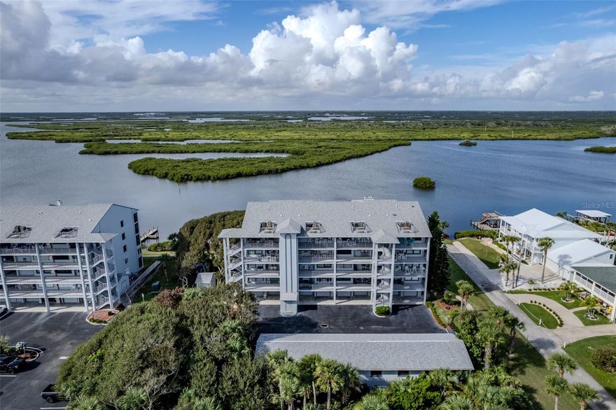 Prepare to be amazed by the spectacular river and ocean views from this rare 5th-floor condo at Cedar Island Club, where every detail has been thoughtfully designed to bring the coastal lifestyle to life. From the moment you step inside, soaring vaulted ceilings and crown molding create a sense of elegance, while warm hardwood floors flow through the living, dining, and bedrooms. Natural light floods the open-concept layout, leading your eyes straight to the Intracoastal. The kitchen is a chef’s delight, featuring granite countertops, maple cabinetry, stainless steel appliances, and a sweeping ocean view to enjoy while you cook. Tile floors in the kitchen and baths, along with durable LTV flooring in the den/office, offer beauty and practicality. The dining area, second bedroom, and kitchen all share stunning ocean views, while the living room and primary suite capture the serenity of the river. Every room offers a view worth savoring. The screened-in lanai off the living room is west-facing, giving you front-row seats to dramatic sunsets. It’s an ideal spot for entertaining, relaxing, or simply enjoying the river breezes and watching dolphins and manatees play. An additional enclosed den/office off the primary bedroom provides the perfect space for unobstructed river views. The primary suite also features a walk-in closet. The community offers resort-like amenities: private boat launch and boat storage, fishing and crabbing from the docks, and easy access to the beach walkover, Mary McLeod Bethune Park, tennis courts, and playground. The surrounding lagoon is a haven where manatees and dolphins gather, adding to the magic of the setting. Whether you’re starting the day with a sunrise over the Atlantic, watching the shuttle launches from your lanai, or winding down by the wood burning fireplace as the sun sets over the Intracoastal, every moment here feels like a getaway. This is more than a home—it’s a lifestyle, combining comfort, beauty, and adventure in one unforgettable package.