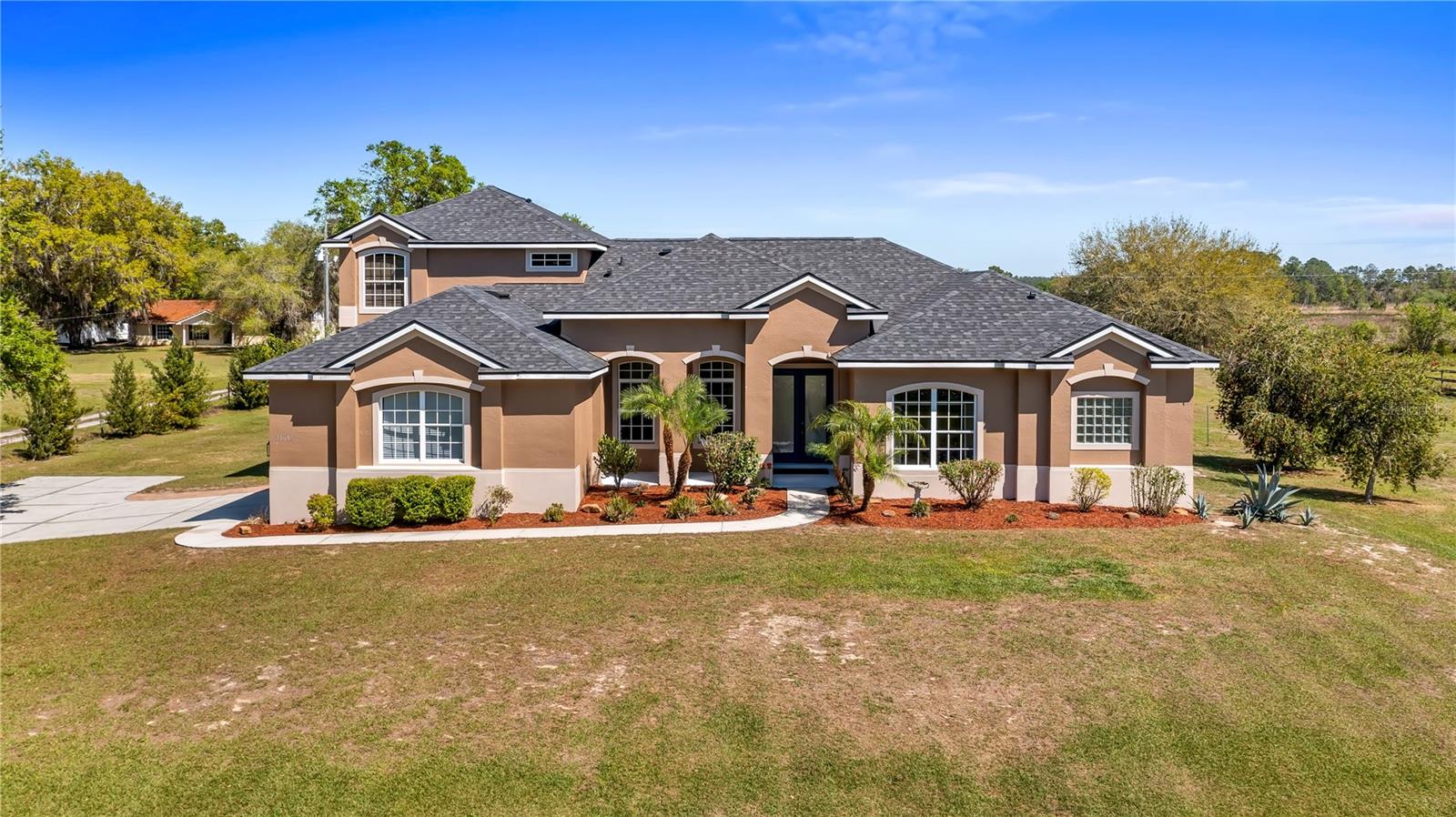 Welcome to your dream home, a stunning five-bedroom, four-bath property on five acres of beautiful land. This exceptional home offers comfort and luxury, with a fantastic floor plan that blends formal and family living spaces. The home provides a peaceful retreat while being close to all amenities you need. Upon entering, you'll be immediately impressed by the spacious layout. The main level features four large bedrooms, each with ample walk-in closet space and natural light. The oversized primary suite is a sanctuary, complete with a generous walk-in closet and a luxurious en-suite bath. For added convenience, the main level also includes two additional full baths, providing ultimate comfort for family members and guests alike. Upstairs, a huge loft offers plenty of room for a home office, entertainment area or additional living space. There is also a private bedroom and a full bath upstairs, ideal for guests or those seeking a bit more privacy. This home is equipped with modern features and upgrades, including a fiber modem installed with speeds of up to 1 gig, ensuring you’ll have fast and reliable internet for work, streaming or gaming. The air-conditioning units have recently been health-checked by Renaldi’s, ensuring the cooling system runs efficiently year-round and another air conditioner installed in garage! The garage has been recently updated with a fresh epoxy floor, providing a clean, durable surface. The roof, well pump and water heater have also been replaced, giving you peace of mind that all the major systems in the home are up to date. For those who love outdoor living, this property has it all. A 36x36x12-foot pole barn with separate 200-amp service and water offers endless possibilities for hobbies, storage or workspace. Whether you're a car enthusiast, a DIYer, or simply need extra space for your toys, this barn has you covered. Enjoy your mornings in the beautiful lanai, which provides an eastern view where you can watch stunning sunrises. On occasion, you may even be treated to the sight of a rocket launch! The lanai also offers a peaceful view of the no-bank lake, adding to the serene atmosphere of this private estate. Wildlife lovers will feel at home here, as the property is a sanctuary for numerous species of birds, including hawks, owls, cardinals, eagles, falcons, and sand cranes. It’s a nature lover’s paradise. For those who enjoy outdoor recreation, the property features an 18,000-gallon saltwater sports pool with water features and lights, all powered by a variable-speed Pentair pool pump. Whether you're swimming laps, relaxing, or hosting friends, this pool is the spot to unwind. The yard is a gardener's dream, with fertile soil that allows for year-round vegetable gardening. The garden area is ready to produce a bountiful harvest, allowing you to enjoy fresh, homegrown produce throughout the year. Additionally, a shed with air conditioning provides a comfortable space for your gardening tools and equipment. This 5-acre parcel includes 3.5 acres of dry, usable land, with no flood insurance required. With no HOA, you have the freedom to make the property your own. The lighted, gated and freshly sealed paved driveway leads to the home and ensures privacy and security. This stunning property offers the balance of seclusion, modern amenities and natural beauty, a one-of-a-kind place to call home. Don’t miss the opportunity to own this incredible estate and see it today!