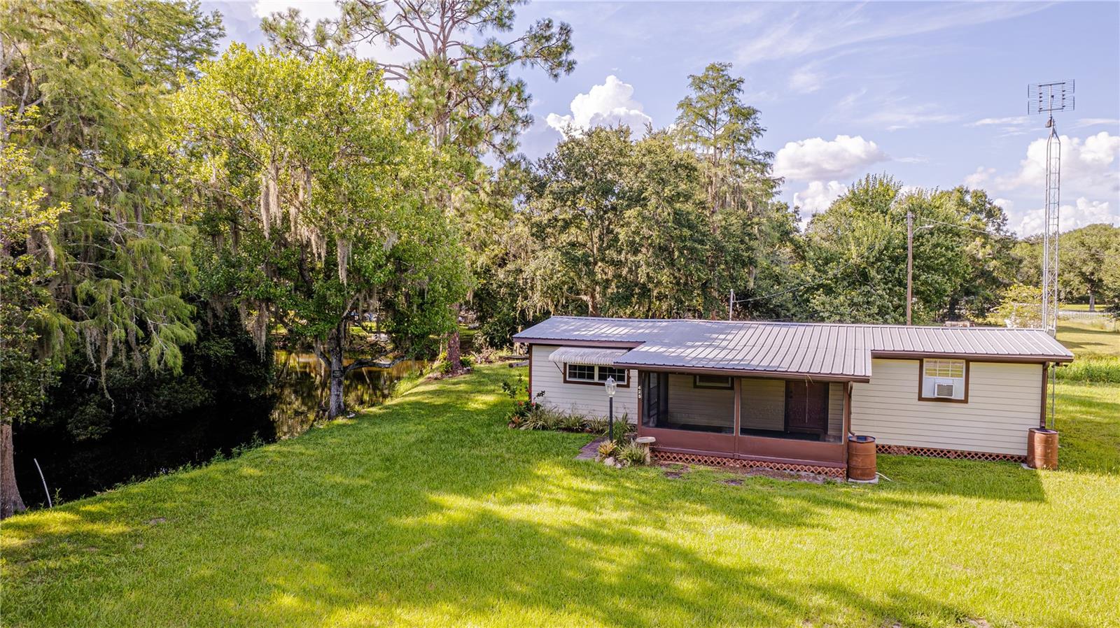 PEACEFUL CABIN, TUCKED DOWN AN OAK-CANOPY ROAD......with water views & beautiful birds. !!!MAKE SURE TO READ TO THE VERY END FOR A SPECIAL SIDENOTE!!! Where are my hunters?? Fishing Fools?? The kitchen has been replaced with newer cabinets (some with pull-outs), counters, & backsplash. BOTH MINI SPLIT A/C UNITS ARE NEWER & all window a/c units will stay. HOME HAS A METAL ROOF & GUTTERS. We have TWO SCREENED-IN PORCHES.....front and back. The living room is oversized......could easily be made into a private bedroom or area of the home. The laundry room has washer & dryer hook-ups.....exterior consists of VINYL & CONCRETE BOARD SIDING. A partially enclosed pole barn with a concrete pad would make an ideal storage area......with a utility sink in place, it would make a great outside cleaning area. Park the ATV underneath or expand to make a great kennel! The well has a NEW PUMP & water softener, as well as extra storage in its pumphouse. The front is fenced with a private gated entry.....beautiful Cypress, Oak & Palm trees bring many types of birds......even a Bald Eagle's nest within view. Complete the fencing for pups, plant a garden for self-sufficiency, & truly savor the peace & quiet of nature. THE HOME NEXT DOOR IS ALSO AVAILABLE FOR SALE.......415 1ST STREET!! Have family that you need close by? Maybe some in-laws who would like their own space......Make us an offer on both and have great space & opportunity. Welcome to Kenansville Florida!! Lake Marian boat ramp is less than a mile away. RV HOOK-UP IS IN PLACE!!!