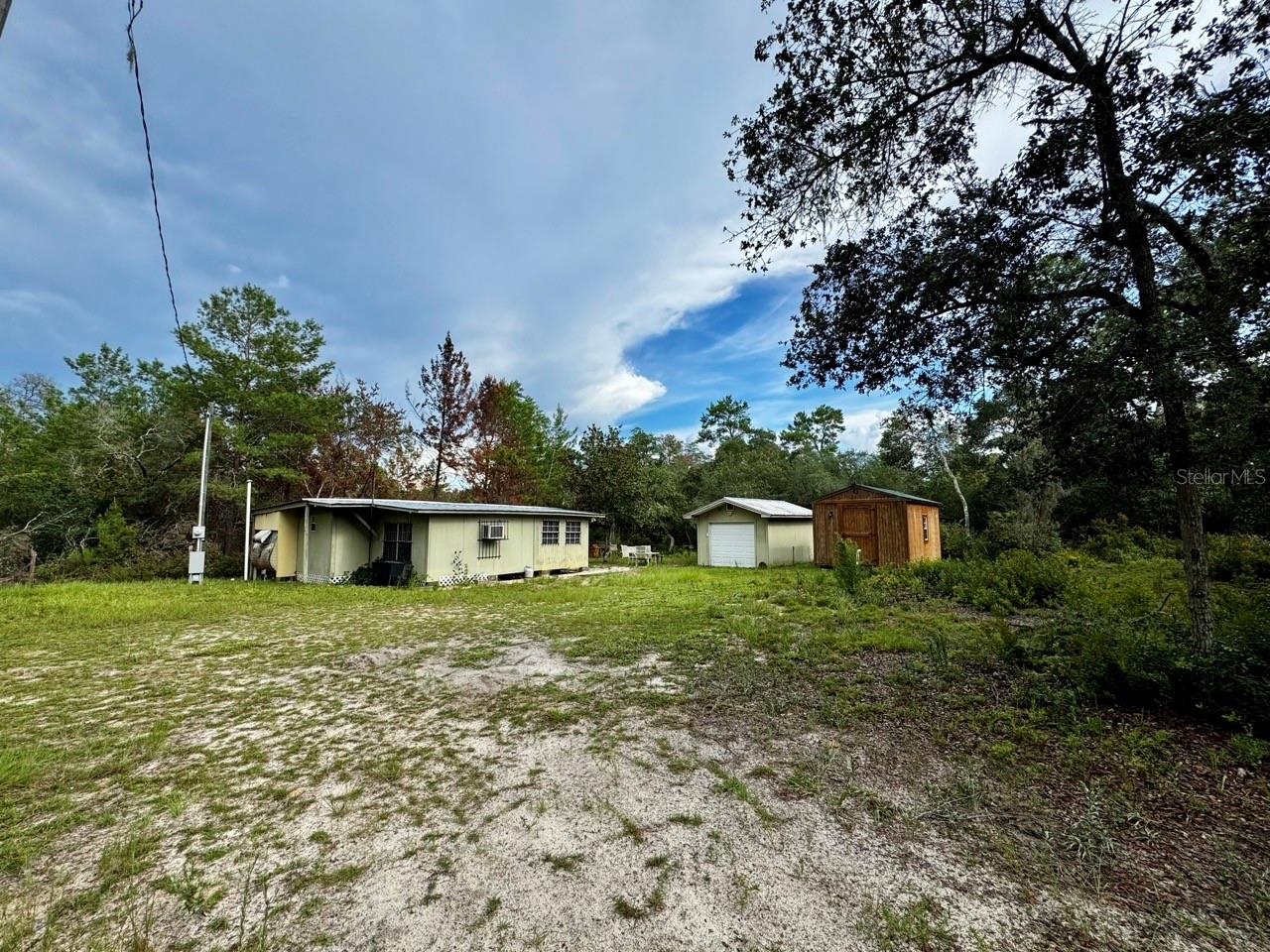 WOODS RETREAT SEEKING NEW OWNERS! Deep in the forest, you will find this retro MH with living room, dining room, bathroom, bedroom, and screened porch addition. The mobile home portion features kitchen, half bath, and a room that can be used as a second bedroom or office. Has a 1-car garage with power, and an 11’ x 20’ storage building with power and window unit that could easily be converted to a bunkhouse situated on 1 lot with an additional 3 lots under separate tax ID, all totaling .79 of an acre. Pack your bags, grab your gear, and get ready for hunting season! Located in the Ocala National Forest near miles of ATV trails and 1 mile away from the boat ramp to the Ocklawaha River!