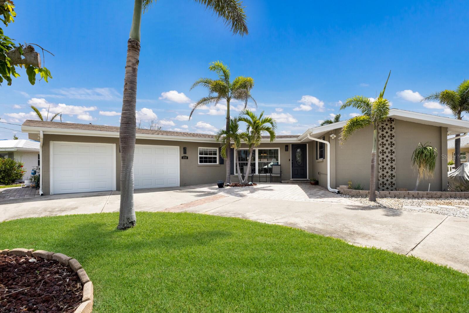 Welcome to Coastal Living at Its Finest in San Remo Shores! Nestled in one of the area's most desirable waterfront communities, this home in San Remo Shores offers the ultimate boater’s lifestyle with wide, deep-water canals and no fixed bridges providing quick access to Palma Sola Bay and the Gulf of Mexico. From the moment you arrive, you’ll appreciate the ample parking provided by a half-circle driveway and an additional parking pad beside the garage. Step through the front door into a light-filled open concept layout, where expansive canal views greet you and flow seamlessly through the living, dining, and kitchen areas ideal for entertaining. The beautifully remodeled kitchen is sure to impress any chef, featuring coastal-inspired shaker cabinetry, a propane gas range, quartz countertops, and a striking seascape tile backsplash. Just off the kitchen is a flexible bonus space perfect for a home office, mudroom, or even a third bedroom by county records. Relax in the spacious living room while enjoying tranquil water views. A conveniently located half bath is perfect for guests and accessible to the outdoor patio through the sliding glass doors. The primary suite offers an ensuite bath, terrazzo flooring, a walk-in closet, and an additional secondary closet. The second bedroom also features terrazzo flooring and generous space. Throughout the home, you'll find double-pane windows, including impact-rated in select areas adding to peace of mind and energy efficiency. Additional highlights include a roof replaced in December 2017, propane gas tankless water heater, 2-car garage with workshop and laundry hookups, well irrigation system for yard and landscaping, 10,000 lb boat lift just waiting for your next adventure on the water. Enjoy waterfront dining, catch your dinner, or take in a famous Gulf Coast sunset. You’re just minutes from historic Cortez Fishing Village and the sandy beaches of Anna Maria Island, where the charm of Old Florida still lives on. And best of all, this home remained high and dry during last year’s storms. Don’t miss your chance to own a slice of Florida paradise in this premier boating community.