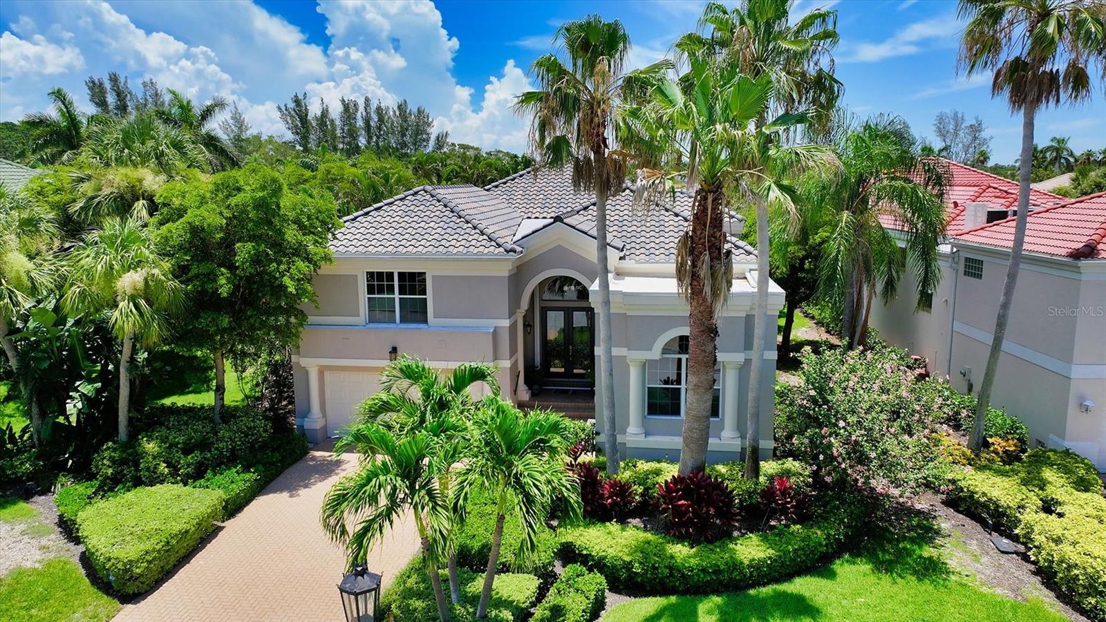 One or more photo(s) has been virtually staged. Situated in the highly sought-after maintenance-free community of Queens Harbour, behind the gates of Bay Isles, this updated lakefront home perfectly captures the ease of Florida living. A 2023 tile roof adds peace of mind, while a smart split floor plan includes three en-suite bedrooms, a half bath, and a versatile den/office that can serve as a fourth bedroom. The interiors feel bright and welcoming with 12–15’ ceilings, neutral tones, and elegant architectural details. Wood-look porcelain tile flooring enhances the living room, dining room, den/office, and first-floor bedrooms, combining durability with style. The kitchen features stainless steel appliances, a center island with second sink, updated hardware, and a breakfast nook with bay window views of the pool and lake. The primary suite enjoys direct lanai access, tranquil water views, and a spa-like bath with dual vanities, soaking tub, and walk-in shower. Outdoors, the screened lanai offers a heated pool and spa with a peaceful lake backdrop, plus a refreshed covered sitting area with a new tongue-and-groove ceiling and accent wall—perfect for relaxing or entertaining year-round. Residents enjoy exclusive access to the Bay Isles Beach Club, with its private beachfront, cabanas, and members-only amenities, along with optional memberships for golf, tennis, and the Harbourside Marina with deepwater slips. This home sustained no hurricane damage or water intrusion. This is Longboat Key living made simple—beautiful, low-maintenance, and ready to enjoy.
