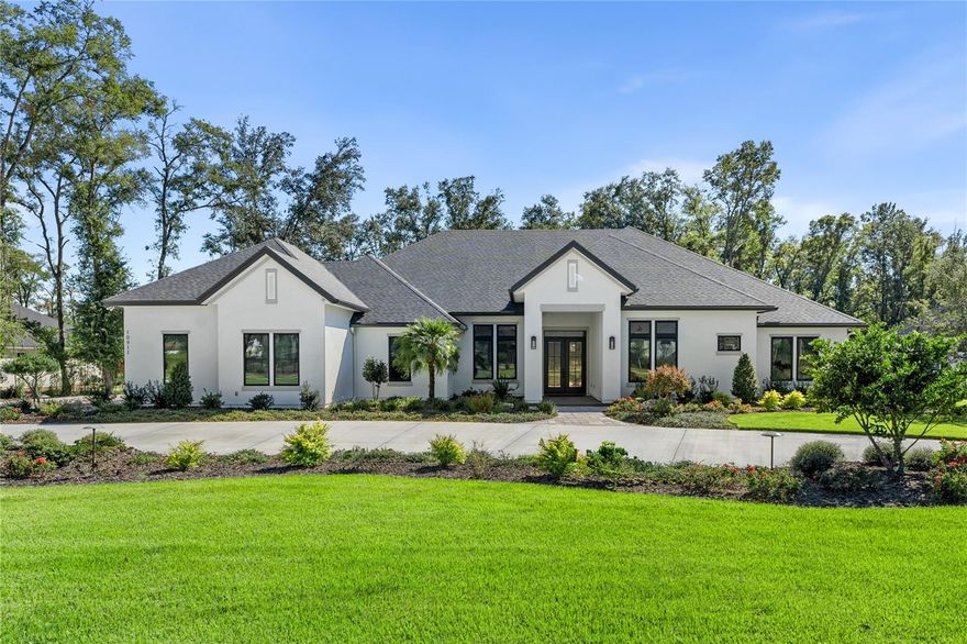 This exquisite 4 bedroom, 4.5-bathroom custom home, built by Barry Bullard, that sits on a beautifully landscaped 1-acre lot is more than a residence, it's a lifestyle. A spectacular, expansive driveway welcomes you to the property, complete with a circular drive that creates a stately entrance and stunning curb appeal. The property features an open three-way split floor plan, accented by custom Origin windows and doors, and stunning luxury vinyl flooring throughout. The double glass entry doors lead to a great room that offers a 12-foot coffered ceiling, a stacked marble gas fireplace, and elegant lighted built-ins. Adjacent to the great room is a flex space, perfect for a piano, extra seating, or a formal dining area. The dining room includes a bar area with lighted shelving, an under-counter beverage refrigerator, and a stunning chandelier. The gourmet kitchen is a chef’s dream, equipped with two islands—one with waterfall quartz counters and the other featuring a commercial-grade "The Galley" sink with dual designer faucets. Custom cabinetry surrounds the high-end stainless steel appliances, including a Wolf gas cooktop, wall oven, microwave, and a Sub-Zero refrigerator/freezer. A discreet walk-in pantry, hidden behind a stylish cabinet door, offers ample space with additional custom cabinets, countertops, shelving, and a second refrigerator. To the left of the foyer, a hallway leads to a custom coat closet, a private study, an elegant guest half-bath, and an oversized laundry room with an island, ample space for storage and organization and built-in custom pet kennels. The breathtaking primary suite features a tray ceiling, and a grand bathroom with large dual vanities, a two-entry walk-in shower, a freestanding tub, and extra-large porcelain tile floors and walls. The suite also includes an additional flex room, which can be used as a nursery, gym, or second office. There are two additional bedroom wings: one with two spacious en suite bedrooms with luxurious bathrooms and walk-in closets while the other offers a flex room, an adjacent bedroom, and a full bath, making it perfect for use as a private in-law suite, complete with its own entrance from the lanai. The home is light and bright with large windows and doors that invite in the natural light creating a warm and welcoming atmosphere. The expansive, covered screened lanai is finished with travertine tiles and features a saltwater heated pool and spa with sun shelf for lounge chairs, a stacked travertine stone wall with three waterfalls, and a summer kitchen outfitted with a gas grill, a two-burner cooktop, and a stunning backsplash. Additional upgrades include an audio system and TVs installed by Sound Ideas, a whole-house generator, exterior lighting, and custom automatic blinds throughout the home. Extending the outdoor living space, the beautifully manicured fenced backyard provides the perfect setting for gatherings with family and friends. The oversized three-car garage includes built-in storage and a workbench. Located in Oakmont, one of Gainesville's most sought-after communities, offering luxury living and fabulous amenities.