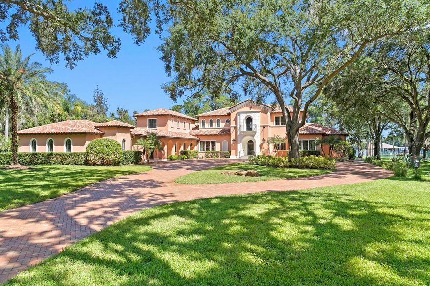 Nestled along the tranquil shores of Lake Keystone, this exceptional gated estate offers a blend of timeless architecture, refined appointments and coveted lakeside living. Offering 180 feet of pristine lake frontage and a sprawling 4.35-acres, this manicured property delivers privacy and serenity. Built by Fechtel Homes, classic architectural design provides elegant details throughout, with wood-beamed coffered ceiling, warm wood accents and stunning lake views. Light filled living spaces on the first level are accompanied by soaring 11+ foot ceilings, media room, executive office/library with fireplace and formal dining room. An elegant foyer leads to the gracious living room and family room with fireplace, offering flowing spaces and lake views. A chef’s kitchen will inspire elevated culinary expression with top-of-the-line appliances and granite counters, expansive center island, impressive wine refrigeration and butler’s pantry. Equipped with Wolf, Sub-Zero, Bosch and Viking appliances, including the added benefit of a commercial refrigerator and 6-burner range, along with a breakfast area. The gracious first floor primary suite retreat delivers a personal sanctuary with lake views, luxurious bath and dual custom closets. Additional features on the first level include a mudroom and generous laundry room with dual washers and dryers. The second level features the private spaces with 3 additional bedrooms with en suite baths and a casita/guest suite featuring living area, kitchenette, additional bedroom, full bath, and private access, perfect for guests, extended stay or multigenerational living. Captivating Florida living welcomes you outdoors through a spacious loggia to an outdoor kitchen, expansive terrace and spa that overlook meticulously maintained grounds and tranquil lake beyond. A private composite dock is equipped with electricity and offers multiple covered entertaining areas and a boat ramp for endless access to lake adventures. Additional highlights include 3 garages accommodating up to 9 cars. The detached 5-car garage provides a climate controlled interior, plus additional storage. Embrace a superior lake lifestyle in this extraordinary estate offering architectural craftsmanship and abundant natural beauty in this Odessa community. With over 4 acres of picturesque land, the property also offers the opportunity for equestrian use — buyer to verify all zoning and land use permissions with the county.