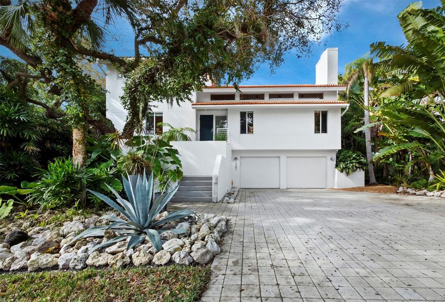 With award winning design and striking contemporary elegance nestled in the lush landscape of Longboat Key, this renovated modern home in a secure, gated community offers three levels of luxury and private access to Cranes Bayou with a fully equipped dock and 80 feet of water frontage. The interior spans more than 3,320 a/c square feet across an open layout with sight lines from the entry to the water, chic minimalist design, and modern architecture that showcases natural light and an ideal indoor/outdoor lifestyle.
On the main level, the elevated entry opens to a massive great room with a vaulted double-height ceiling that creates a dramatic sense of space. The living area flows seamlessly to the kitchen, ingeniously designed in a wraparound layout to promote flow on all sides, opening to the living room, adjacent dining room, and terrace overlooking the water. The kitchen boasts striking exotic wood cabinetry, expansive counter space, dual sinks, and premium stainless steel appliances including gas range, additional wall oven, integrated microwave, and side-by-side refrigerator freezer. Just past the kitchen, a full wall of floor-to-ceiling glass sliding doors open to a terrace that spans the entire width of the home for additional lounge and dining space overlooking the saltwater pool and bayou beyond. On the upper level, dual owners' suites offer luxurious retreats, each with double sliding glass doors that open to private water-facing balconies, large walk-in closets, and generous en suite bathrooms outfitted with chic modern features. Outside of the primary owners’ suite, a mezzanine overlooking the great room offers a private perch for relaxation or workspace. The ground level, currently arranged as a gym and den, is an expansive room with walk-out access to the pool and deck, where additional outdoor lounge space is protected by the three-story cage. Exceptional contemporary finishes, bamboo flooring, recessed lighting, and an elevator that serves three floors add to the luxurious comforts within the home. The landscape design and lighting are noteworthy enhancements that showcase both the home and the setting. Located within the private gated community of Bay Isles, owners also have exclusive access and use of the Bay Isles Beach Club on the Gulf of Mexico. Room Feature: Linen Closet In Bath (Primary Bedroom).