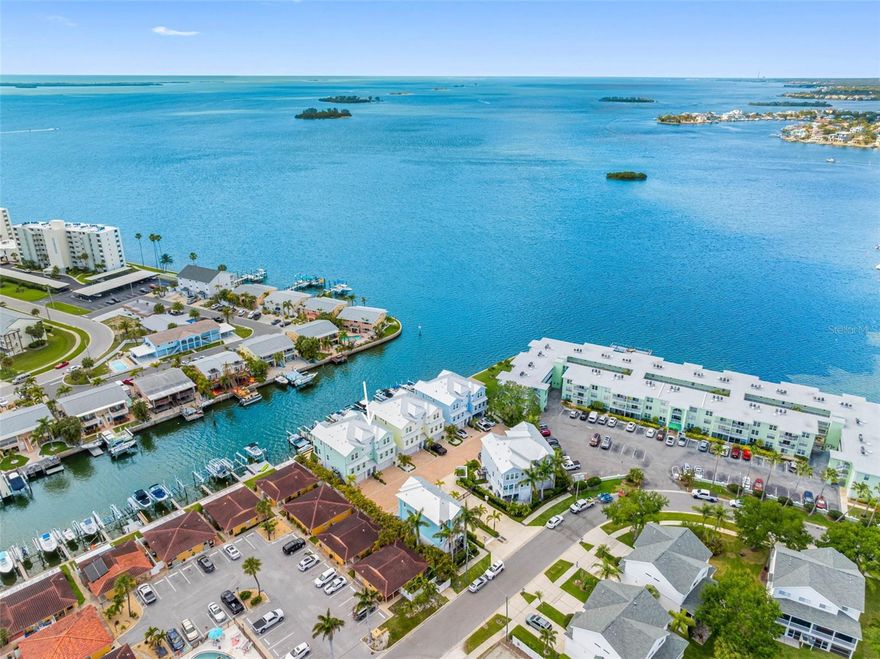 Waterfront Dunedin living with sweeping Gulf views, a private boat slip, elevator and refined coastal design. In Sea Palms, an exclusive gated waterfront enclave built in 2021 and comprised of just nine luxury townhomes, this residence offers a blend of privacy, elegance and convenience in the heart of Dunedin, one of Florida’s charming golf-cart-friendly towns. This 2,264-square-foot home features an open floor plan with upscale coastal finishes and expansive window walls that capture stunning views of the Gulf and nearby barrier islands. Offering three bedrooms, three baths and an oversize two-car garage, the residence also includes a private elevator for ease and functionality. The gourmet kitchen serves as the centerpiece of the home, featuring premium cabinetry, quartz countertops, Bosch stainless-steel appliances, an induction range, a built-in microwave and a walk-in pantry. The adjacent dining area provides ideal space for everyday living and entertaining. The main level includes a spacious guest bedroom with a built-in closet and a full bath nearby, ideal for visitors. Neutral designer finishes, motorized shades and engineered hardwood flooring enhance the home throughout. The third floor features the primary suite with spectacular water views, a large walk-in closet with custom organizers, and a spa-inspired bath with a glass-enclosed shower, dual-sink quartz vanity and private water closet. An additional bedroom or office with a walk-in closet and en-suite bath completes the level. The ground level offers a spacious two-car garage with ample room for vehicles, beach gear and storage, plus a private rear covered travertine lanai with motorized screens and a private waterfront patio leading directly to your boat slip with an Activity Deck and a 12,000 lb. Lift, electric, water and dock, ideal for boating, fishing and sunset views. Residents also enjoy a private courtyard with fire pits and grilling areas. Just a short distance to Honeymoon Island, Pinellas Trail and the vibrant heart of downtown Dunedin, 604 Sea Court offers not just a home but a lifestyle.