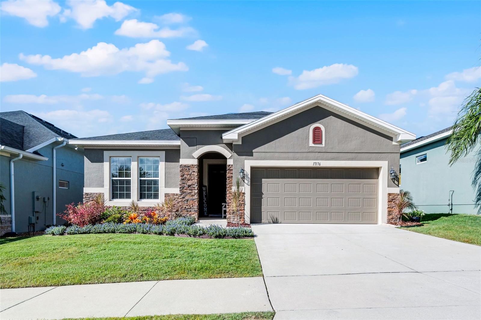 This 3 bedroom, 2 bathroom home with a versatile flex space is more than a place to live, it’s a place to belong. From the welcoming stone accented exterior to the manicured landscaping, every detail sets the tone for warmth and comfort. Tile floors guide you through a bright, open layout where life naturally comes together. The kitchen is the heart of the home, featuring quartz counters, upgraded cabinetry, a stylish backsplash, and a pendant lit island that invites family and friends to gather. Meals flow effortlessly into the dining room, where memories are shared around the table. Just beyond, a built in workstation offers a convenient spot to stay organized, pay bills, or work from home. The living room opens to an extended screened paver lanai, pre plumbed for a summer kitchen, where mornings begin with coffee and evenings end with soft Florida breezes. Lush landscaping forms a living wall, creating a private and serene retreat, while the fenced yard adds the perfect finishing touch, with room for play, pets, or quiet moments outdoors. The primary suite is a retreat of its own, filled with natural light and peaceful views of John’s Lake. A spa inspired bathroom with dual vanities and a walk in shower completes the sanctuary. Two additional bedrooms and a second bath ensure comfort for family or guests, while the versatile flex space adapts to your lifestyle, whether it be a home office, reading nook, or creative studio. Practical touches such as the mudroom drop zone, laundry room with cabinetry, and a two car garage make daily living effortless. Modern smart home features include a Vivint system, Ring doorbell, WiFi enabled garage door opener, smart lock, and an alarm system. Life here extends beyond your front door with community amenities that include a resort style pool, cabana, playground, and barbecue area. Located just minutes from shopping, dining, top rated schools, the Clermont Chain of Lakes, and the West Orange Trail, this home offers not just a place to live, but a place where life feels inspired.