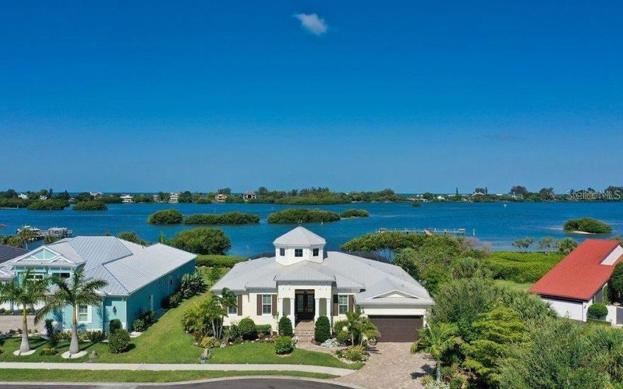 Unobstructed bayfront views and refined coastal luxury define this exceptional waterfront residence in the gated Bayside community. Custom-built in 2017 by Rob Allegra and ideally positioned on a private cul-de-sac between Sarasota and Venice, this home offers a rare opportunity to experience the best of Florida’s Gulf Coast lifestyle. Sweeping views of the Bay and Intracoastal Waterway greet you upon entry, while the dramatic great room features a striking cupola with soaring 22-foot ceilings, wraparound windows, architectural beams, and detailed millwork that beautifully frame the waterfront setting. Pocketing impact sliders seamlessly open the living space to an expansive covered lanai where breathtaking sunsets, dolphins, and gentle coastal breezes create an unforgettable everyday backdrop. The open chef’s kitchen is designed for both entertaining and daily living, offering high end stainless appliances, a gas cooktop with pot filler, wine cooler, abundant cabinetry, and an oversized quartz island. Outdoor living shines with wood-paneled ceilings, crema pro leathered marble flooring, a gas fire pit, and a fully equipped outdoor kitchen with grill and beverage refrigerator. The solar and heat pump-heated saltwater lap pool and spa, outdoor shower, and private dock with lift complete the ultimate waterfront retreat. The primary suite enjoys beautiful water views and features a sitting area, double tray ceiling, dual custom walk-in closets, and a luxurious bath with double vanities and walk-in shower. Two additional en-suite bedrooms, a den or office, and a powder room provide comfort and flexibility. Wood-look tile flooring runs throughout, complemented by impact windows and doors, a smart-enabled security system, whole-home generator, and water conditioning system. Located just minutes from Casey Key, Nokomis Beach, Oscar Scherer State Park, and the Legacy Trail, this home offers effortless access to beaches, boating, dining, and recreation. An extraordinary waterfront residence where luxury, comfort, and coastal beauty come together, offering the lifestyle you’ve always imagined.