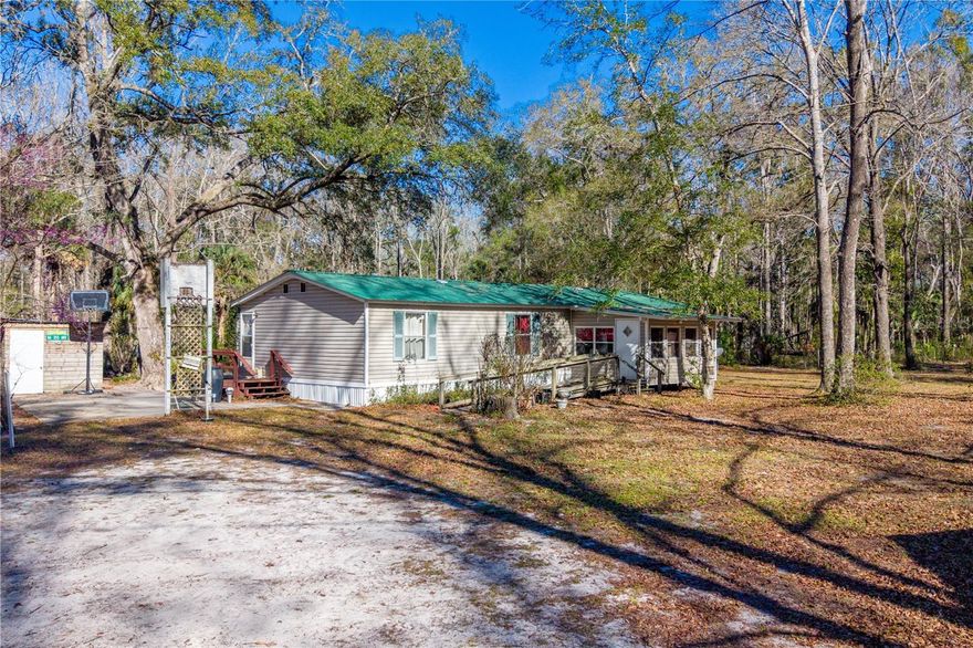 3-bedroom, 2-bath manufactured home situated on 5 fully fenced and gated acres in Old Town. The home features an open floor plan, wheelchair accessibility, walk-in closets, and an enclosed Florida sunroom. A pot belly stove provides supplemental heat. Outdoor amenities include a 27x54 above-ground pool with large wraparound wood deck and covered sitting area, multiple concrete slabs, a 42x52 pole barn with concrete slab and lean-tos, enclosed storage areas, water softener system, and several fruit trees. Located just minutes from a public boat ramp with access to the Suwannee River and approximately 20 minutes to the Gulf of Mexico. Plenty of space for animals, equipment, gardening, or recreational use. Schedule your private showing today.