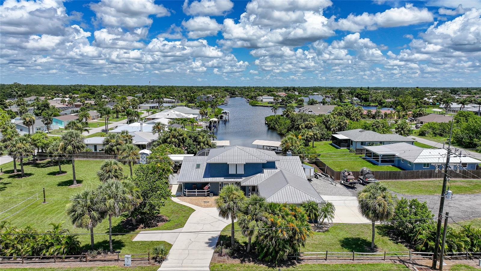 Rare waterfront gem on 1.17 acres with 100 feet of saltwater canal frontage, offering a quick 10–15 minute boat ride to open water from your private 55-foot dock with dual boat lifts. This expansive property stretches from block to block and is partially fenced, featuring a storage shed and plenty of space for all your extras, including an RV or camper with its own electrical hookup. The home sits perfectly centered on the property with two separate driveways providing dual access to the 4-car garage, offering convenience and versatility.
Inside, you are welcomed by a spacious layout with a foyer, formal living room and dining room. The updated kitchen sits at the heart of the home perfect for gatherings boasting tons of cabinet and counter space, positioned between a flexible sitting area and the cozy living room with a fireplace. Off the living space is a bonus room with panoramic canal views... bright, versatile space perfect for relaxing, entertaining, or creating a hobby room. The first floor features a split plan with the primary suite, family room, living room, formal dining, breakfast nook, one guest bedroom, and one full guest bathroom. The primary suite offers lanai access, dual closets, dual vanities, and a walk in shower for those who cherish their own personal space. Upstairs, an additional living area, two bedrooms one has dual closets, and a full bathroom create a private wing of the home, ideal for guests, or extended family to enjoy their own space. Outside, the views are breathtaking as you look straight down the canal from the screened paver pool deck. The sparkling blue salt water pool shares this incredible view, while the screened area includes a covered lanai for shaded relaxation. Beyond, a true cabana style porch with four ceiling fans provides a breezy, all weather spot perfect for hosting family and friends. At the dock, every detail has been considered, no detail missed. First lift accommodates up to 16,000 pounds, while the other is currently set up for multiple jet skis but can easily be converted for another boat while being covered from the sun. A fish cleaning station makes preparing your fresh catch a breeze. This home not only offers beauty and function but also peace of mind with hurricane windows throughout and never-used flood prevention barriers. Combining safety, practicality, and dreamy waterfront living, this property is also conveniently located near shopping, dining, beaches, and more. Call today to schedule your private tour.