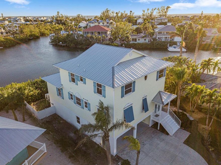 Elevated Waterfront Living with short term rentals allowed on Anna Maria Island! Welcome to Lake LaVista Beach House, a lovely turnkey furnished waterfront retreat offering 270-degree views of serene Lake LaVista. Situated at the end of a quiet cul-de-sac, this 4-bedroom, 4-bathroom home boasts 4,278 square feet under roof (2,564 under air) with direct water access, complete with a private dock and boat lift. From your backyard, you’ll enjoy sitting on your terrace watching ospreys catching breakfast, as well as manatees, and dolphins in their natural habitat. Nestled on the coveted north end of Anna Maria Island, this elevated, turnkey-furnished pool home combines coastal elegance with relaxed island living. As a popular short term rental property, nightly or weekly short-term rentals are allowed, (rental history is available upon request) making this home an ideal investment opportunity or private getaway. The property’s tropical landscaping provides a private oasis, while its proximity to Anna Maria’s charming boutiques, restaurants, and pristine beaches ensures convenience and entertainment. Step inside to soaring ceilings and breathtaking lake views. The open-concept main level is perfect for entertaining, featuring a spacious great room with sliding doors leading to a screened lanai, a dining area and kitchen with a breakfast bar. The primary bedroom is located on the main level with an ensuite bathroom, double vanities, a soaking tub, a walk-in shower, and two walk-in closets (one lockable for owner use). The primary suite opens to a private balcony with tranquil water views. An additional bedroom with an ensuite bathroom is located on the main level. The upper level offers two more ensuite bedrooms, providing ample space for family and guests. A large garage includes a separate storage area that can also serve as a secure owner’s closet. Multiple outdoor spaces, both covered and open, invite you to relax and soak in the Florida sunshine. The screened porch off the living room leads to a heated pool, equipped with a new heater and pump installed in late 2024. The private dock with a boat lift is perfect for fishing, wildlife watching, or launching your next Gulf of Mexico adventure. This meticulously maintained home is move-in ready and comes with a proven history of successful short-term rentals, complete with future bookings in place. Whether you’re seeking a personal retreat or a lucrative investment property, Lake LaVista Beach House offers the best of island living. Don’t miss this rare opportunity to own a slice of paradise on Anna Maria Island. Schedule your private showing today!