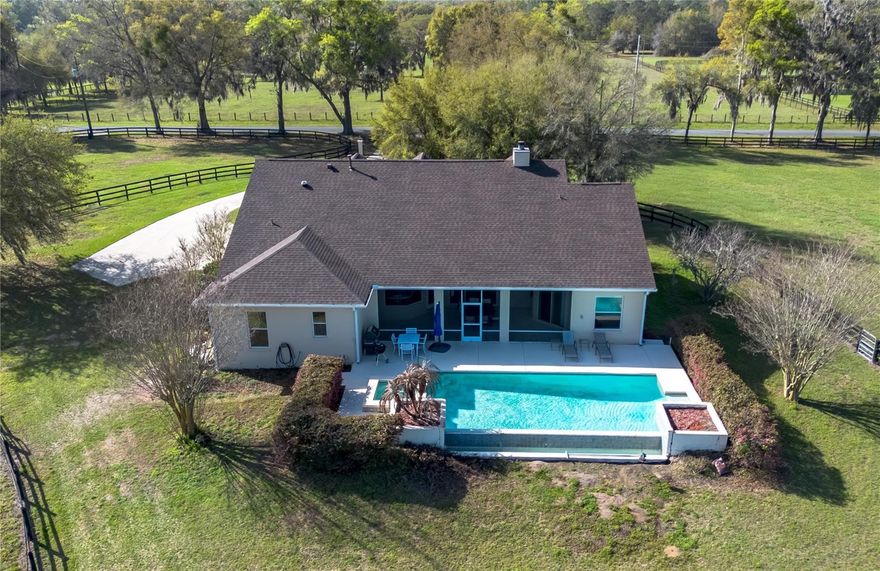 Nestled at the heart of NW Ocala’s vibrant horse country, this well-appointed horse farm is set on just over 10-acres of gently rolling land within the equestrian neighborhood of Golden Farms. Fenced and gated with two entrances along a quiet dead-end road, the property features a line of trees along the front perimeter for added privacy. Down a curved driveway towards the front of the property is the inviting 3-bedroom, 2-bath block home accented by mature landscaping, a spacious covered country-style front patio with ceiling fans, and side-entry 2.5-car garage. Inside, the home is light and bright with an open, split-bedroom floor plan, high ceilings with tray accents, and wood flooring that runs throughout the main spaces. The living room features a high-performance clean-burning wood fireplace that creates an inviting atmosphere. Those who enjoy cooking will love the well-appointed kitchen, which features abundant cabinet and counter space, stainless steel appliances, gas range, and a large breakfast bar– all positioned to flow easily into dining and living areas, ideal for both everyday living and entertaining. The split-bedroom layout ensures privacy throughout, with a spacious primary suite that includes dual walk-in closets and a private en-suite bath with a built-in vanity, garden tub, and glass-door shower. A surround-sound speaker system is in place throughout, making it easy to enjoy music or set the ambience no matter where you are in the home, with plenty of options for adding in additional speakers. Outside, the screen-enclosed patio overlooks the private infinity-edge pool and spa, designed to capture expansive views of the surrounding pasture. This outdoor space is perfectly suited for relaxing or entertaining while enjoying the peaceful setting year-round. An on-demand generator is in place to keep some of essentials powered even during sudden power outages. Equestrian amenities are thoughtfully laid out throughout the property, including an 8-stall center-aisle barn with feed room, tack room, wash rack, hot water, and a fly spray system. A separate entrance is in place for direct barn access, adding to the utility. A total of 7 paddocks are established with 3-board fencing and no-climb wire, offering flexibility for turnout and training. Ideally located just 10 minutes from the World Equestrian Center (WEC) and 13 minutes from HITS, this farm is perfect for those looking to take get the most out of some of the area’s most exciting competition venues and still be nearby a variety of tack and feed stores, equestrian service providers, and world-class veterinary care. Both Golden Ocala Golf & Equestrian Club and Golden Hills Golf Club are also just minutes away, offering additional opportunities to enjoy the year-round sunshine on world-class golf courses. This property offers a rare opportunity to enjoy space, privacy, and a well-equipped farm layout ready to support a variety of disciplines– schedule your showing today!