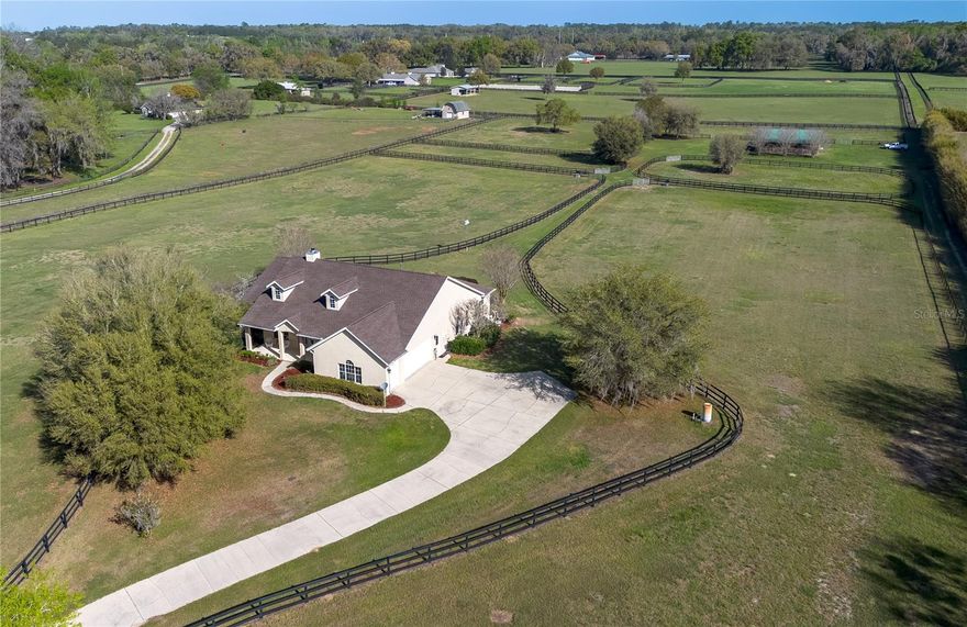 Nestled at the heart of NW Ocala’s vibrant horse country, this well-appointed horse farm is set on just over 10-acres of gently rolling land within the equestrian neighborhood of Golden Farms. Fenced and gated with two entrances along a quiet dead-end road, the property features a line of trees along the front perimeter for added privacy. Down a curved driveway towards the front of the property is the inviting 3-bedroom, 2-bath block home accented by mature landscaping, a spacious covered country-style front patio with ceiling fans, and side-entry 2.5-car garage. Inside, the home is light and bright with an open, split-bedroom floor plan, high ceilings with tray accents, and wood flooring that runs throughout the main spaces. The living room features a high-performance clean-burning wood fireplace that creates an inviting atmosphere. Those who enjoy cooking will love the well-appointed kitchen, which features abundant cabinet and counter space, stainless steel appliances, gas range, and a large breakfast bar– all positioned to flow easily into dining and living areas, ideal for both everyday living and entertaining. The split-bedroom layout ensures privacy throughout, with a spacious primary suite that includes dual walk-in closets and a private en-suite bath with a built-in vanity, garden tub, and glass-door shower. A surround-sound speaker system is in place throughout, making it easy to enjoy music or set the ambience no matter where you are in the home, with plenty of options for adding in additional speakers. Outside, the screen-enclosed patio overlooks the private infinity-edge pool and spa, designed to capture expansive views of the surrounding pasture. This outdoor space is perfectly suited for relaxing or entertaining while enjoying the peaceful setting year-round. An on-demand generator is in place to keep some of essentials powered even during sudden power outages. Equestrian amenities are thoughtfully laid out throughout the property, including an 8-stall center-aisle barn with feed room, tack room, wash rack, hot water, and a fly spray system. A separate entrance is in place for direct barn access, adding to the utility. A total of 7 paddocks are established with 3-board fencing and no-climb wire, offering flexibility for turnout and training. Ideally located just 10 minutes from the World Equestrian Center (WEC) and 13 minutes from HITS, this farm is perfect for those looking to take get the most out of some of the area’s most exciting competition venues and still be nearby a variety of tack and feed stores, equestrian service providers, and world-class veterinary care. Both Golden Ocala Golf & Equestrian Club and Golden Hills Golf Club are also just minutes away, offering additional opportunities to enjoy the year-round sunshine on world-class golf courses. This property offers a rare opportunity to enjoy space, privacy, and a well-equipped farm layout ready to support a variety of disciplines– schedule your showing today!