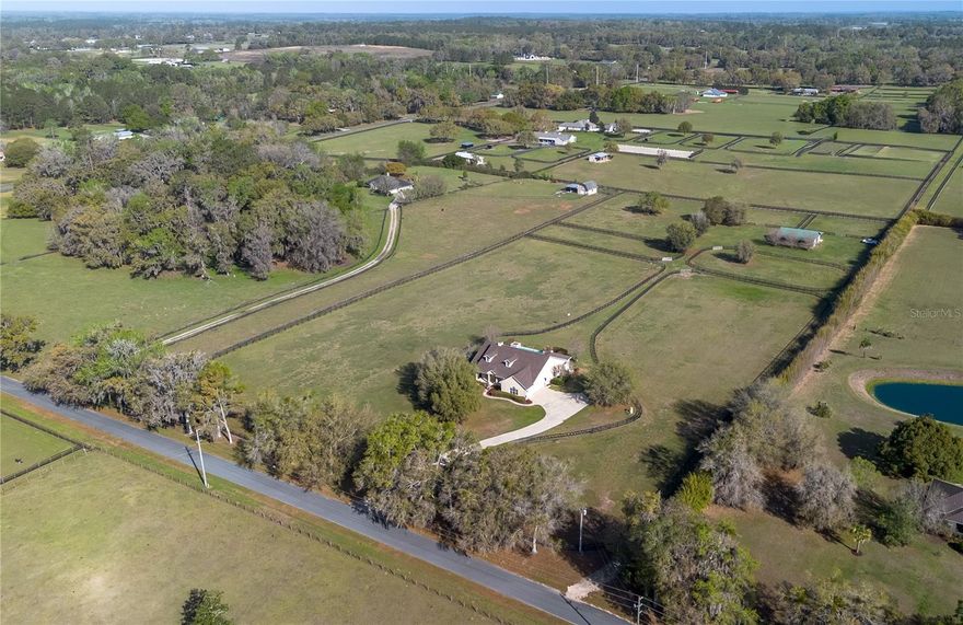 Nestled at the heart of NW Ocala’s vibrant horse country, this well-appointed horse farm is set on just over 10-acres of gently rolling land within the equestrian neighborhood of Golden Farms. Fenced and gated, the property features a line of trees along the front perimeter for added privacy. Down a curved driveway towards the front of the property is the inviting 3-bedroom, 2-bath home accented by mature landscaping, a spacious covered country-style front patio with ceiling fans, and side-entry 2-car garage. Inside, the home is light and bright with an open, split-bedroom floor plan, high ceilings with tray accents, bamboo flooring that runs throughout the main spaces. The living room features a lovely Eilete NexGen Hybrid Fireplace, a clean-burning wood fireplace that creates an inviting atmosphere. Those who enjoy cooking will love the well-appointed kitchen, which features abundant cabinet and counter space, stainless steel appliances, gas range, and a large breakfast bar– all positioned to flow easily into dining and living areas, ideal for both everyday living and entertaining. The split-bedroom layout ensures privacy throughout, with a spacious primary suite that includes a large walk-in closet and a private en-suite bath with a built-in vanity, garden tub, and glass-door shower. Outside, the screen-enclosed patio overlooks the private infinity-edge pool and spa, designed to capture expansive views of the surrounding pasture. This outdoor space is perfectly suited for relaxing or entertaining while enjoying the peaceful setting year-round. Equestrian amenities are thoughtfully laid out throughout the property, including an 8-stall center-aisle barn with feed room, tack room, wash rack, hot water, and a fly spray system. A total of 7 paddocks are established with 3-board fencing and no-climb wire, offering flexibility for turnout and training. Ideally located just 10 minutes from the World Equestrian Center (WEC) and 13 minutes from HITS, this farm is perfect for those looking to take get the most out of some of the area’s most exciting competition venues and still be nearby a variety of tack and feed stores, equestrian service providers, and world-class veterinary care. This property offers a rare opportunity to enjoy space, privacy, and a well-equipped farm layout ready to support a variety of disciplines– schedule your showing today!