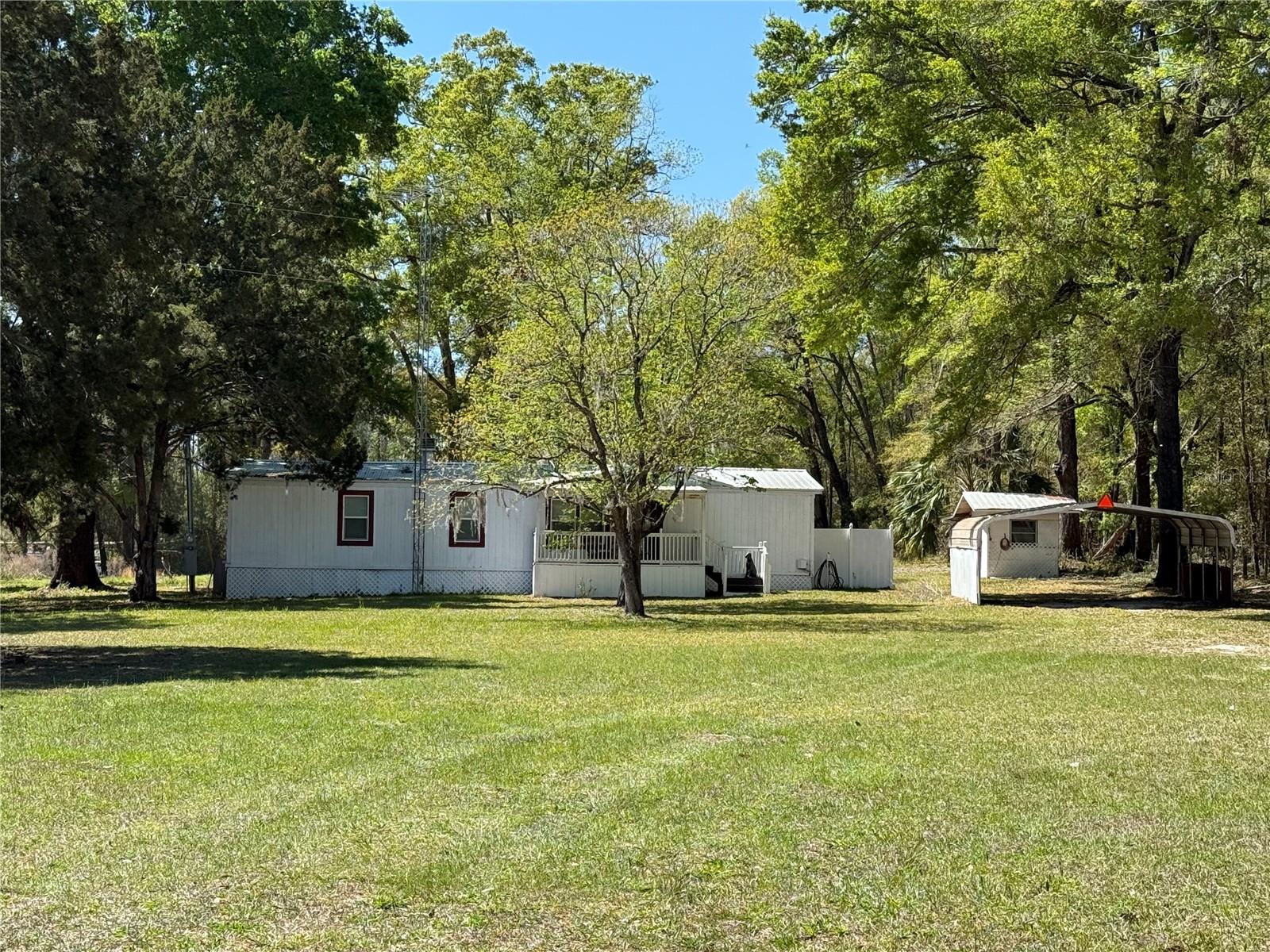 3BR/2BA Mobile Home with fireplace on 2 acres High Springs address Columbia County taxes! Just 1.1 miles past Santa Fe River county line.
The double wide mobile home welcomes you with a nice covered front deck and on duty guard dog statue (not conveying), ideal for greeting guests and deterring solicitors. While the home needs some TLC, it does offer a great start for customizing and adding your own personal touches.
With 2 acres of land, there's more than enough space for gardening, recreation or barn/workshop. There is a smaller metal workshop shed with garage door as well as a small concrete block and floor storage building with small overhang to park a mower or implements.
Open-concept living offers a cozy atmosphere and abundant natural light with wood burning fireplace in the great room. The kitchen offers ample cabinet and counter space, making meal prep enjoyable.
Split floor plan has two bedrooms with walk in closets and hall bath at one end, and the master suite with own entrance at the other. The primary suite features a private ensuite full bath and a separate walking closet. Just ad a screen door for cool days and turn off the central AC. This suite offers flexibility for guests, family, or even a in home office.
The home needs new carpet. Upgrades were ongoing but were not finished.
For someone who wants land but close to all the offerings of High Springs, Alachua, Gainesville & Lake City has to offer; and a easy 30 minute drive to the Gulf (Cedar Key or Steinhatchee) for salt water fun. 1.6 miles from Oleno State Park. 4.4 miles to Camp Kulaqua. 21 miles to Lake City. 32 miles to Gainesville for everything medical, education and shopping.
If you're looking for a home with space and potential, this one is worth a look. Schedule a tour today.
No HOA and no major restrictions this property is perfect for a family who has horses, chicken or kids who need space to run. 1984 MHs qualify for loan process.