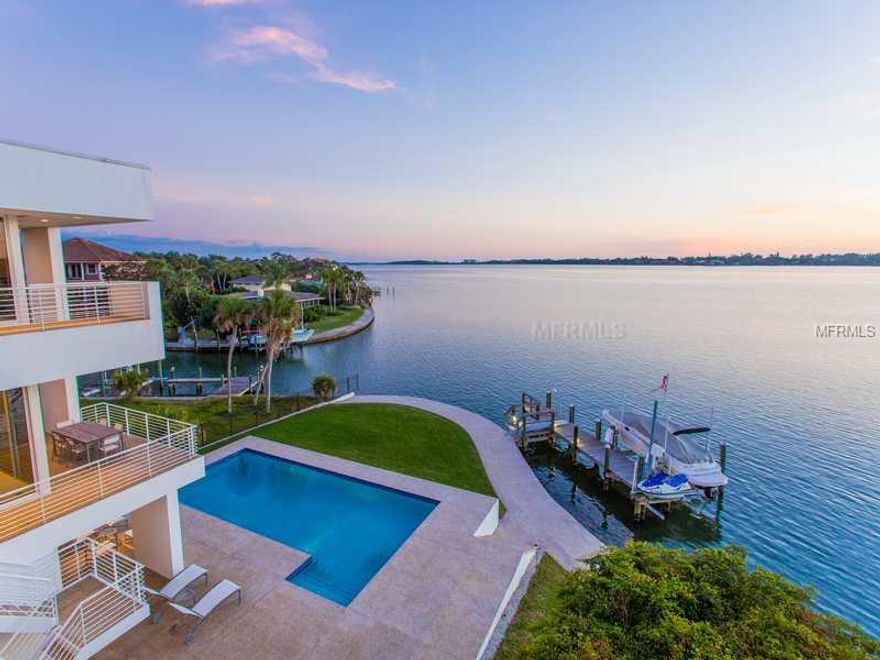 Commanding incredible views of Little Sarasota Bay, this stunning Bayfront home is a breathtaking expression of modern architecture, custom-designed by acclaimed Architect Guy Peterson. Expansive walls of glass, clean lines & angular details place special focus on the captivating water views experienced from almost every room of this magnificent home. From the moment you step into the open living room with soaring 24' ceiling, oversized fireplace & wet bar, the home's signature Bay views are invited through grand glass walls. A perfect union of relaxed waterfront living & grand entertaining, the thoughtfully-designed & richly appointed living spaces include the Chef's kitchen with Neff cabinetry, black galaxy granite counters, & Sub Zero/Dacor/Bosch/Thermador appliances, formal dining room, spectacular office, bonus & exercise rooms, 1,000 bottle wine room, & private elevator. The truly luxurious master suite boasts a lavish bath with dramatic two story glass shower, Jacuzzi tub & limestone counters, & private Bayfront terrace with shimmering water views, while three additional bedrooms afford the comfort of family & guests. The finishing touch to your waterfront lifestyle is the spectacular outdoor living areas, including 40' pool with expansive deck, & private boat dock with 14,000 lb lift, Jet Ski lift & 133' seawall. This home presents a lifestyle enhanced by soothing Bay breezes & endless sunsets, within easy reach of upscale shopping, fine dining, culture, & world-class beaches.