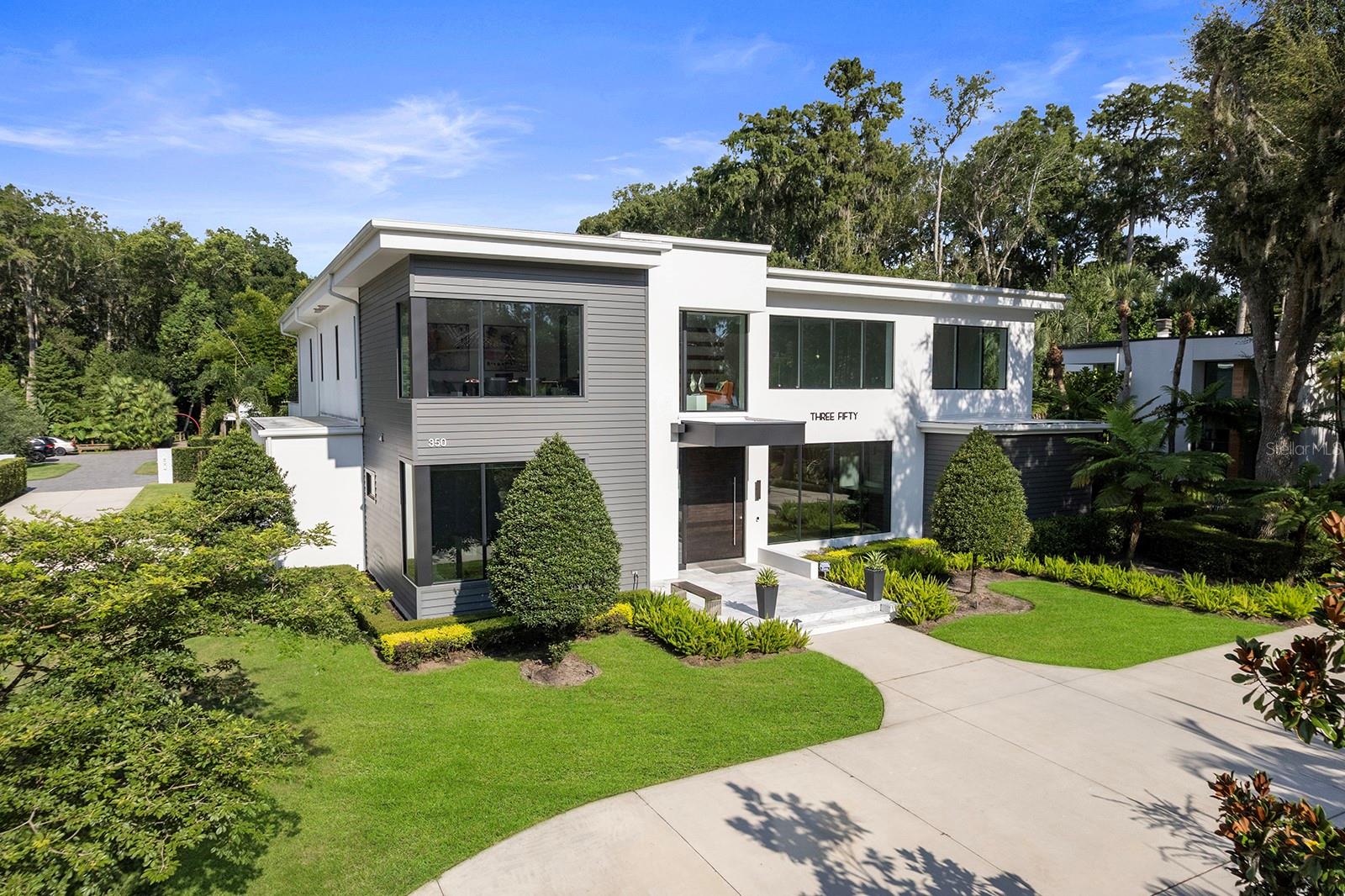 Private setting within the exclusive Lake Maitland Owl Preserve, this spectacular five-bedroom contemporary residence was masterfully built in 2019 by award-winning E2 Homes. A dramatic 12-foot-tall wooden pivot-door makes a striking first impression, opening into a light-filled foyer, gathering, dining, and kitchen wide-open everyday living area with soaring two-story ceilings. A floating staircase becomes an architectural centerpiece, while a sleek linear gas fireplace framed in modern stone design, anchors the living room. Flowing seamlessly into the dining area and chef’s kitchen, the home is designed for both comfort and elevated entertaining. The kitchen is a contemporary showcase, boasting top-of-the-line Wolf and Sub-Zero appliances, a hidden walk-in pantry, and an extraordinary backlit marble feature wall that serves as art and function. Disappearing glass sliders, operated remotely, blur the lines between indoors and out, extending the living space to a covered lanai with multiple sitting and dining areas, a full summer kitchen, and automated screens that protect from sun, rain and the elements. Beyond, a contemporary saltwater pool and spa with water features is framed by a sweeping lawn and thoughtfully designed herb garden with raised beds. The first-floor primary suite offers a serene retreat with a custom walk-in closet and spa-inspired bath featuring a striking tub/shower combination wet room. Also on the main level is a fifth bedroom used as a home office, complete with an en-suite bath. Upstairs living areas include a flexible loft/lounge area at the top of the stairs and leading to two flanked secondary bedrooms, and a fourth junior suite with spacious bath/walk-in closet, then anchored with access to a spacious outdoor balcony overlooking the pool and grounds. Additional highlights include beautiful porcelain tile and elegant dark wood flooring throughout, a three-car side-entry garage, and a circular drive. Secluded, but ideally located, the home offers a tranquil, preserve setting while remaining just minutes from Park Avenue’s fine shops and dining, Maitland’s cultural corridor and with convenient access to top-rated schools, downtown Orlando, and the International and Executive airports.