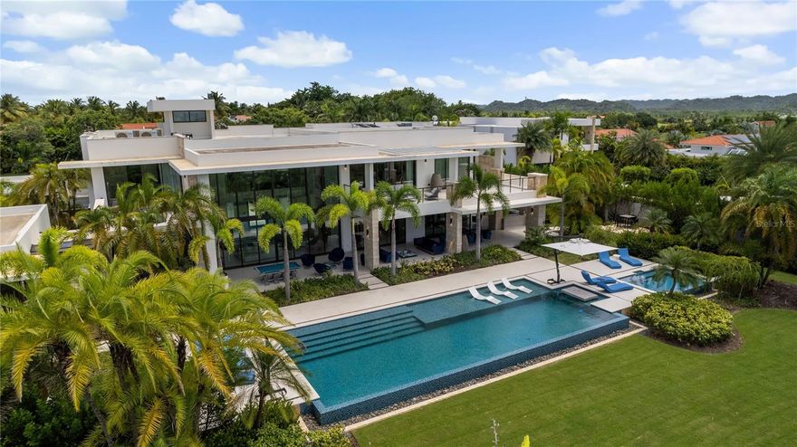 Discover an extraordinary estate in the Legacy neighborhood of Dorado Beach Resort and Club, where luxury, privacy, and exclusivity converge. Set on an expansive 4,800-square-meter property, this home offers an unparalleled amount of land within the resort, making it one of the most unique opportunities on the market. Boasting 16,746 square feet of gross construction, it is situated on one of the most secluded streets, offering a rare sense of peace and tranquility.

What truly sets this estate apart are its rare and custom amenities. A two-lane bowling alley offers a unique entertainment experience that is virtually unheard of in a private property. Alongside this, a private half-basketball court and multiple entertaining spaces make the home ideal for hosting both intimate gatherings and grand events. Outdoors, a covered BBQ kitchen, complete with a custom spit, and a poolside dining table bring alfresco dining to life under the stars.

Inside, the estate unfolds with grandeur, featuring a thoughtful layout designed for both comfort and luxury. On the main floor, you'll find three beautifully appointed bedrooms, each with expansive windows that invite natural light and provide private terraces. Upstairs, two additional bedrooms are complemented by the lavish primary suite, which spans an entire side of the second floor. The primary suite offers ultimate luxury with an oversized private terrace, a spacious walk-in closet with an island, and a spa-inspired bathroom, complete with an outdoor shower for a resort-like experience. Across from the primary bedroom is a private office, providing a serene space for work or relaxation.

In addition to the main living areas, a separate guest suite with its own entrance and serene garden provides privacy and comfort for visitors. For further indulgence, the estate features a dedicated space for a private hair salon, enhancing the home’s one-of-a-kind appeal.

The design elements throughout the property reflect impeccable attention to detail, from the double-height ceilings in the living room to the custom hand-blown chandelier that adds an artistic touch. With its fully integrated audio-visual system, Crestron home automation, and stunning architectural elements, this estate is a masterpiece of modern luxury living.

This exclusive property offers a lifestyle of unmatched sophistication, combining bespoke design, custom amenities, and an extraordinary amount of space within one of the island’s most sought-after resorts, Dorado Beach Resort and Club.