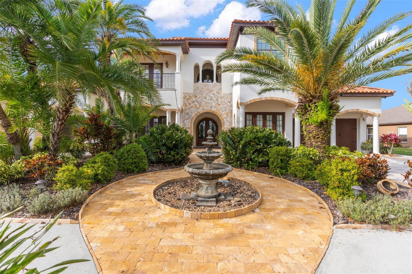 Sensationally Luxurious Lakefront Home with Outdoor Poolside Oasis! Tucked away on Lake Osceola in an exclusive community, this 5BR/5.5BA, 4,882sqft property radiates upscale vibes with stunning Mediterranean-inspired architecture, lavish tropical landscaping, a traditional tile roof, and grand double front doors. Thoughtfully designed for entertaining, the impressive interior dazzles with an organically flowing layout, soaring foyer ceilings, a rustic wrought iron staircase, gleaming Travertine floors, oversized windows, overflowing natural light, crown molding, a beautiful formal dining room, home office with French doors, a cozy wine cellar, and an elegant formal living room with a well-appointed fireplace and custom ceiling. Remodeled to satisfy both foodies and gourmets, the remodeled chef’s kitchen features custom wood cabinetry, stainless-steel French door refrigerator, dual wall ovens, gas stove, attractive backsplash, stylish countertops, center island with prep sink, a huge breakfast bar, pantry, and an adjoining breakfast nook. Weekend get-togethers and birthday parties are sure to be elevated with the exceptional fenced-in backyard, which has a heated swimming pool/spa (screened-in), a convenient newer outdoor kitchen (2022), a firepit, gorgeous decking, and tons of room for lounging. Nautical fun may be achieved with the two-story dock with a boat lift. Relax exploring the lake or simply try your hand at skiing. After being a gracious host, retire to the sprawling primary bedroom with a romantic gas fireplace, two walk-in closets, wrap-around balcony, lovely lake views, and a sumptuous en suite boasting a soaking tub, separate shower, and double vanities. All extra bedrooms are generously sized with attached bathrooms and walk-in closets, while the main-level guest suite also has access to the pool. Additional considerations include a central vacuum system, attached garages, 3 A/C units, second-floor laundry room, butler’s room with room for a refrigerator and second washer/dryer, Steinbrenner School District, close to shopping, restaurants, and more! Check out the video and call now for your tour!