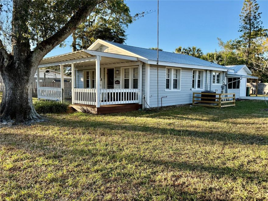 Affordable Florida Living at Its Best! Welcome home to this charming and beautifully updated bungalow that delivers big on comfort, style, and value. The bright, coastal-inspired kitchen is a dream for any home chef, featuring a classic farmhouse sink, Coastal Cupboard cabinetry, Corian countertops, newer appliances, and a breakfast bar perfect for morning coffee or intimate dinners.  The spacious living room offers stylish flooring and plenty of room for entertaining guests or settling in for a cozy movie night. The primary bedroom is thoughtfully designed with an oversized walk-in closet that includes built-in closet space—ideal for a home office, nursery nook, or creative retreat.  The updated bathroom shines with a new vanity, mirror & fresh paint.  A true Florida room adds even more flexibility complete with convenient access to the garage workshop.  Step outside to a huge fully fenced double lot, perfect for pets, play, and outdoor entertaining. Enjoy BBQs on the patio, rinse off in the outdoor shower, and store tools or toys in the shed. The attached carport keeps you dry during summer showers, while the inviting front porch is the perfect spot to relax and watch the sunset.  Additional highlights include solid block construction, a metal roof (2014), newer A/C, updated windows, fresh flooring throughout.  Priced right, move-in ready, and ideally located, this home truly checks all the boxes. Don’t miss your chance to claim your place in the Florida sun—schedule your showing today!