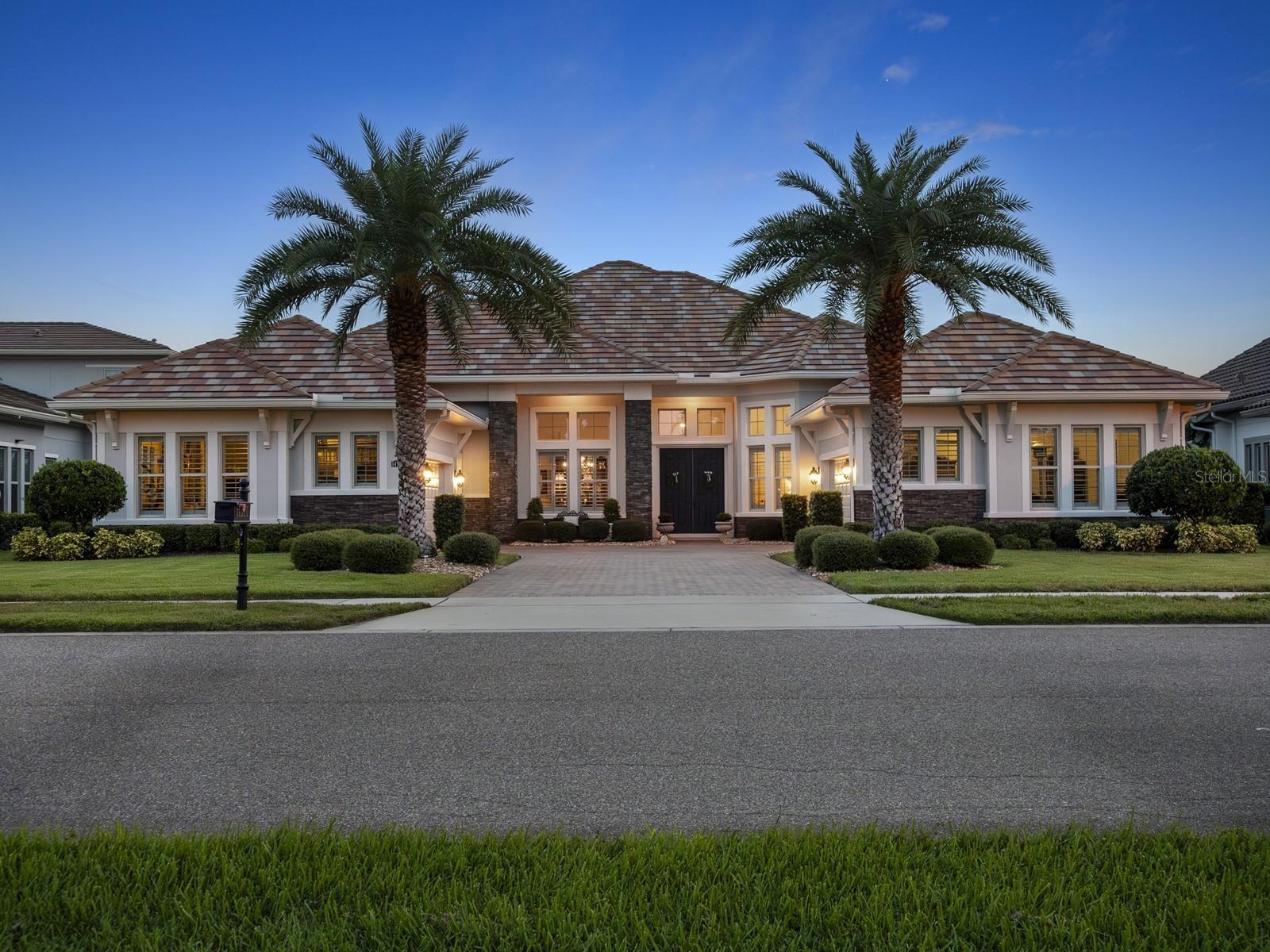 Welcome to 14640 Pylon Court, an extraordinary waterfront home located in the highly sought after gated community of the Isles of Lake Hancock—one of Florida’s most exclusive water ski neighborhoods. This custom-designed residence offers over 4,400 square feet of luxurious living space, five bedrooms, five full and one-half baths, a 4-car garage, and sweeping water views from both the front and back of the home. Set on a premium lot with direct views of the world-renowned championship ski courses, this home offers the ultimate blend of privacy, elegance, and recreational lifestyle. Inside, rich hardwood flooring flows through spacious, light-filled living areas, including a formal dining room with detailed ceilings, a private study, and a great room with soaring ceilings, custom built-ins, a fireplace, and expansive sliding glass doors. The gourmet kitchen features a massive island, gas appliances, double ovens, and ample cabinetry—perfect for both casual family living and entertaining on a grand scale. The luxurious primary suite includes a sitting area with lake views, dual walk-in closets, a soaking tub, walk-in shower, and dual vanities. The first-floor media room offers the perfect space for movie nights or game-day gatherings, while four additional bedroom suites and a balcony complete the home’s thoughtful layout. The expansive screened lanai is ideal for outdoor living, featuring a sparkling pool, summer kitchen, manicured grounds, and tranquil water vistas. As a resident of this exclusive 54-home community, you’ll enjoy access to a residents-only boat ramp, tennis courts, playground, and recreation area. Located just minutes from all of the shopping and amenities at Hamlin, yet tucked away in a quiet, gated enclave, this home offers a rare opportunity to own one of Central Florida’s most sought-after waterfront properties—where luxury meets lifestyle.