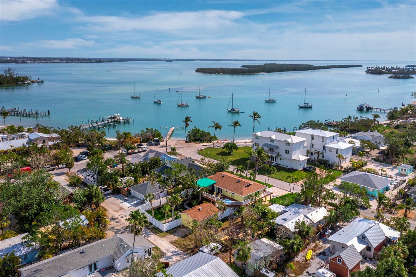 HUGH PRICE REDUCTION!!!Welcome to historic Longbeach Village, the first neighborhood, established on Longboat Key in 1885. As you enter The Village you will notice a variety of architectural home styles from the 1930s to the present day reflecting the diversity of the folks who live here. This wonderful home has stunning water views of Sarasota Bay, The Village harbor with its small public beach, the town dock, and the boat ramp all of which serve as community gathering spots to launch your boat, kayaks, canoes, and view sunrises, sunsets, dolphins, manatees, and aquatic birds. Pelicans love this placid harbor. Capture and immerse yourself in these magical surroundings from the spacious elevated second level front deck. The open concept great room with the three sets of French doors and seven windows is flooded with natural light. The kitchen offers bay views and will be the envy of amateur as well as gourmet cooks. Here you will enjoy a Sub-Zero refrigerator, two drawer Sub Zero freezer, Wolf 5 burner range, large Wolf oven, Miele steam oven, Tanzanian granite counter tops, custom German cabinets, large and deep storage drawers, workstation, and travertine floors. The great room includes an abundance of recessed lighting and a free-standing wood burning fireplace on a raised hearth as well as a dining area with a distinctive wood table, benches, and chairs. The primary bedroom has water views, access to the wrap around deck through sliding glass doors, and a large walk-in closet, en-suite bathroom with striking wood vanity and marble-like glass sink and dual rainfall shower heads. The powder room off the great room has high end fixtures. The guest bedroom has twin beds, a ceiling fan and rolling shades to keep the light out. The adjoining room could function as an office, art studio, or an extra bedroom. The bathroom has a shower stall and a walk-in closet. The oversized two car garage has hurricane reinforced doors, windows, a work bench, ample shelving throughout and peg boards for tools. A composite “wood” deck that is impervious to rot and insects, surrounds the entire house creating massive outdoor living space. The back deck, overlooking a beautifully landscaped yard, has a heated hot tub, a dining area which has a new awning, and a staircase leading to the backyard, guest house/studio, and new two-person barrel sauna in 2023. The guest house/studio was totally renovated by current owners in 2015 with new Hardi Board siding and insulation. It could also serve as a recreation room with pool table etc. All windows throughout the structures are hurricane compliant. Meticulous and impeccable pride in ownership can be found in every detail throughout! From this lovely home you can walk to the beach, five restaurants, and Whitney Beach shopping center. The Centre Shops with dining, boutiques, hair salon, UPS store are about three miles south. Bradenton Beach, with its multiple attractions, is less than 1 mile north. Famous St. Armands Circle is eleven miles south. The Villagers meet once a month from October to April for socializing and gathering updates on LBK activities. Offered furnished, completely outfitted, and move in ready excluding original artwork and some personal items.
